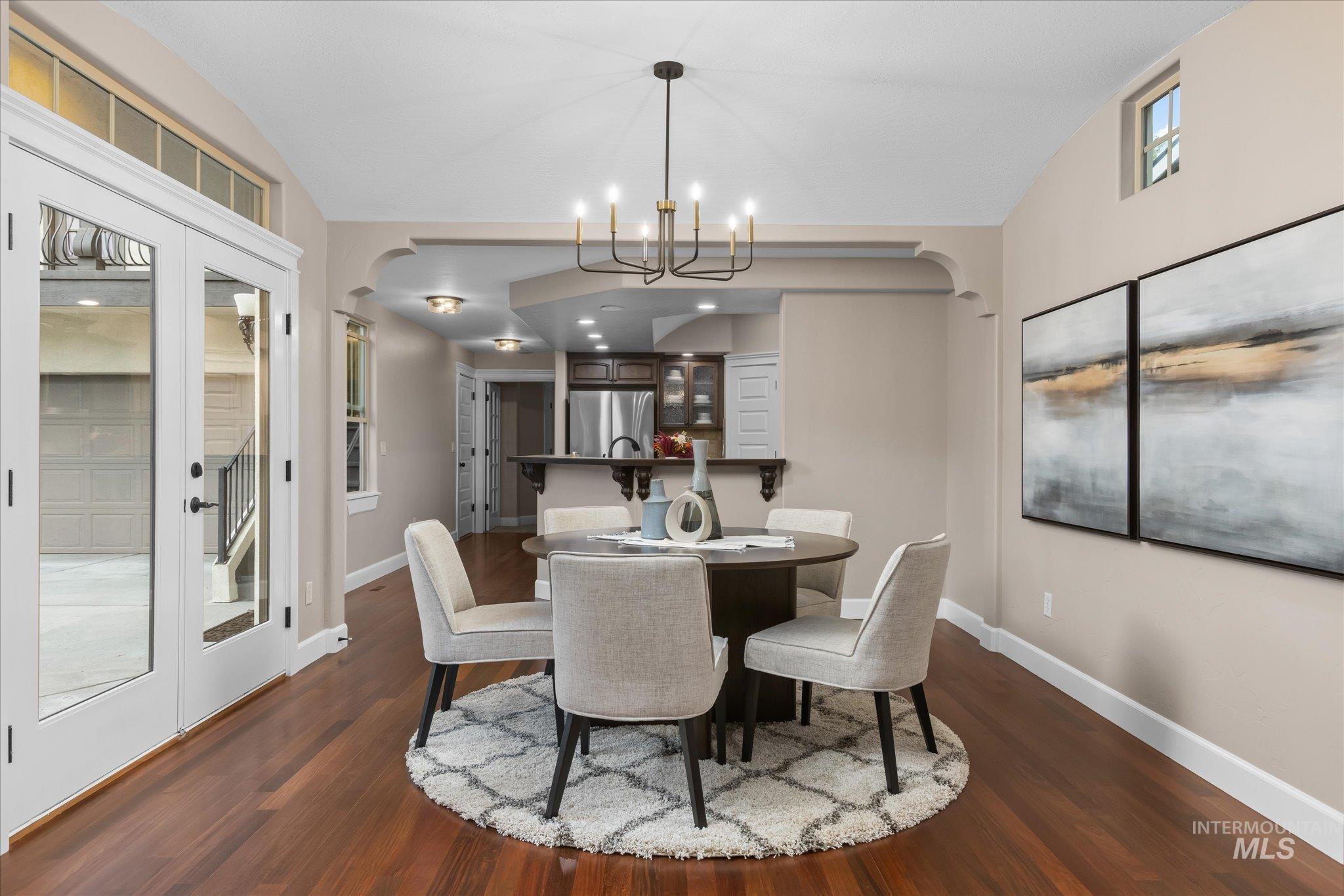 Dining area featuring french doors, dark wood finished floors, arched walkways, vaulted ceiling, and a chandelier