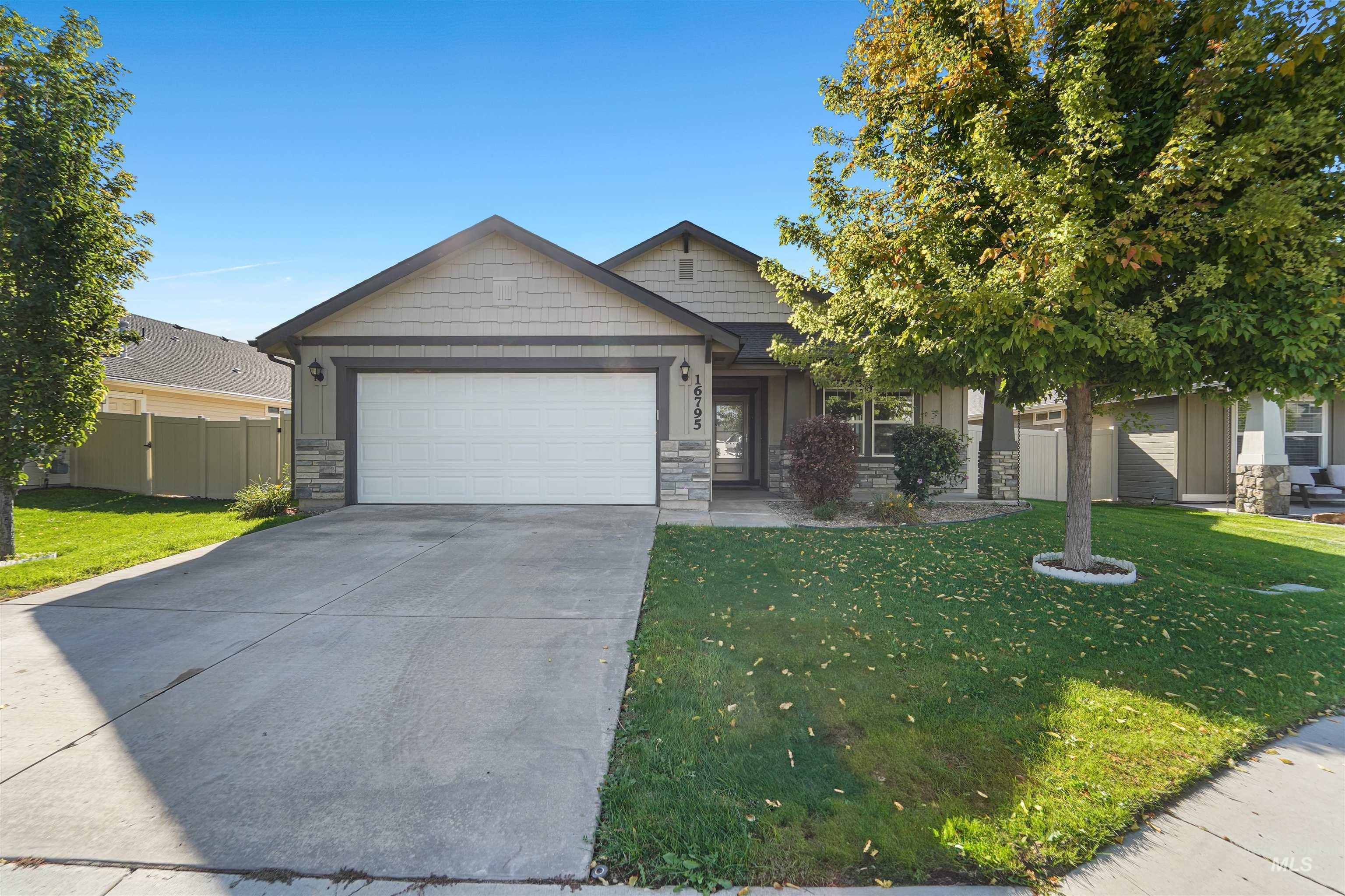 View of front facade featuring stone siding, driveway, and an attached garage