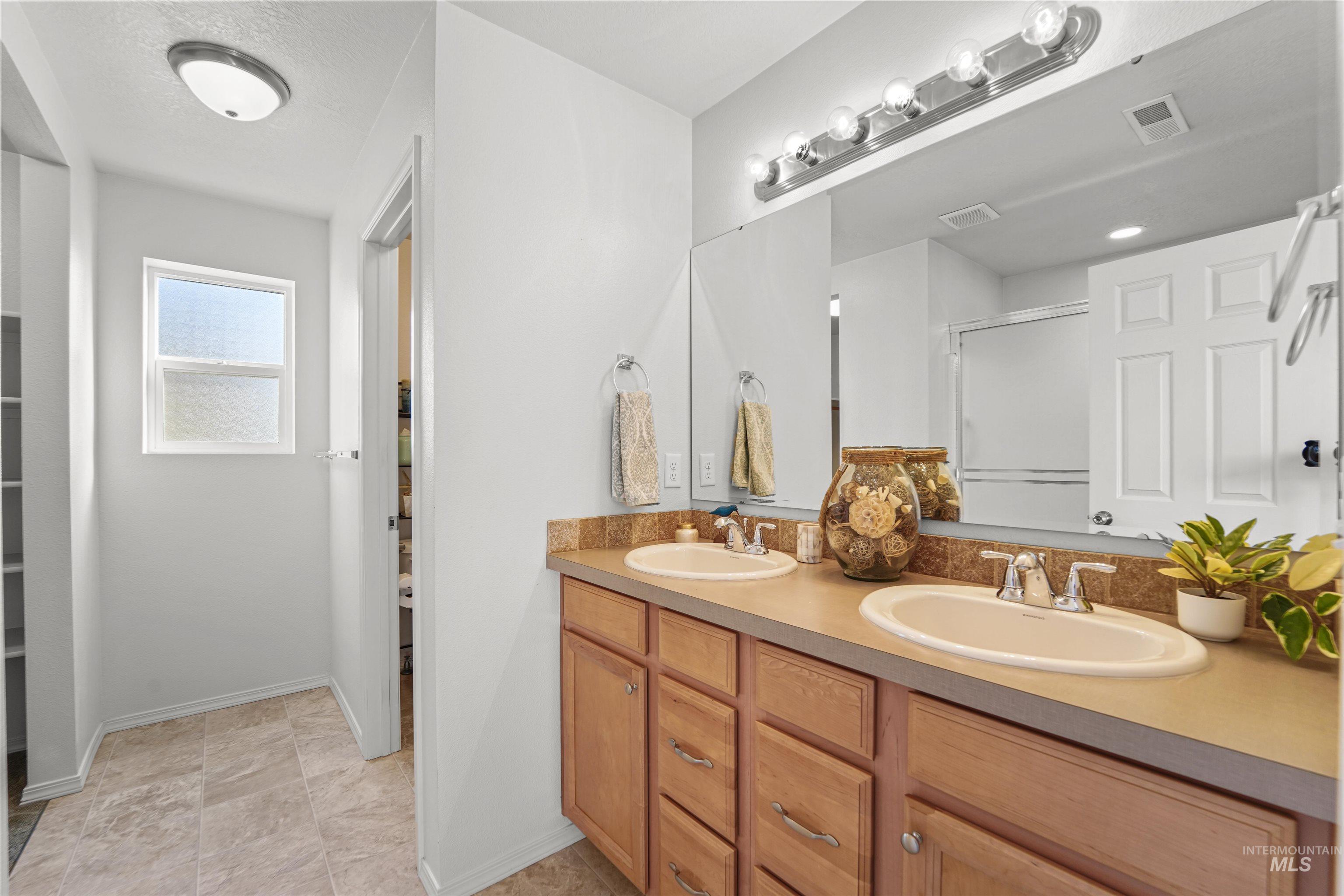 Bathroom featuring a stall shower and double vanity