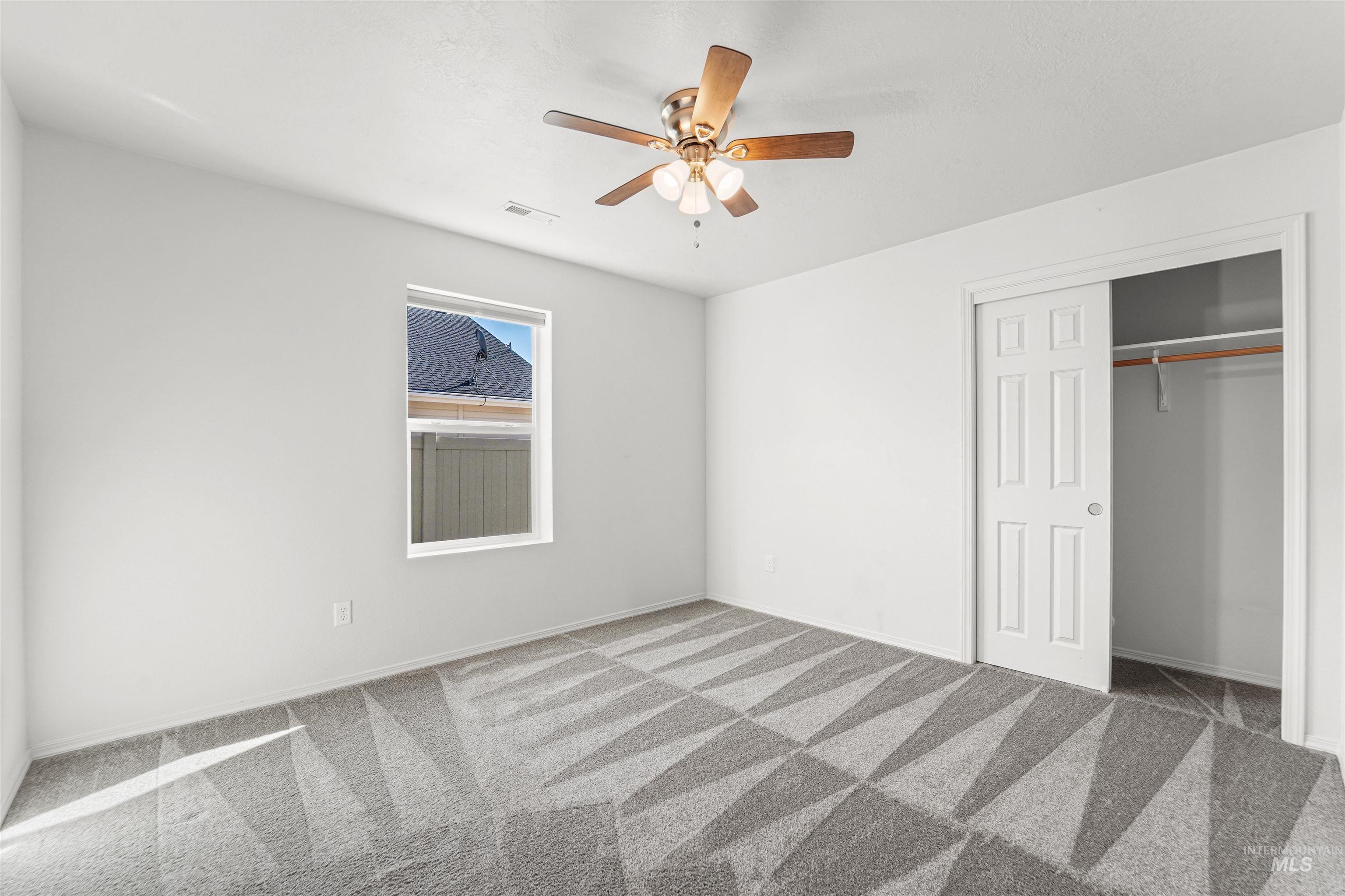 Unfurnished bedroom featuring light colored carpet, ceiling fan, and a closet