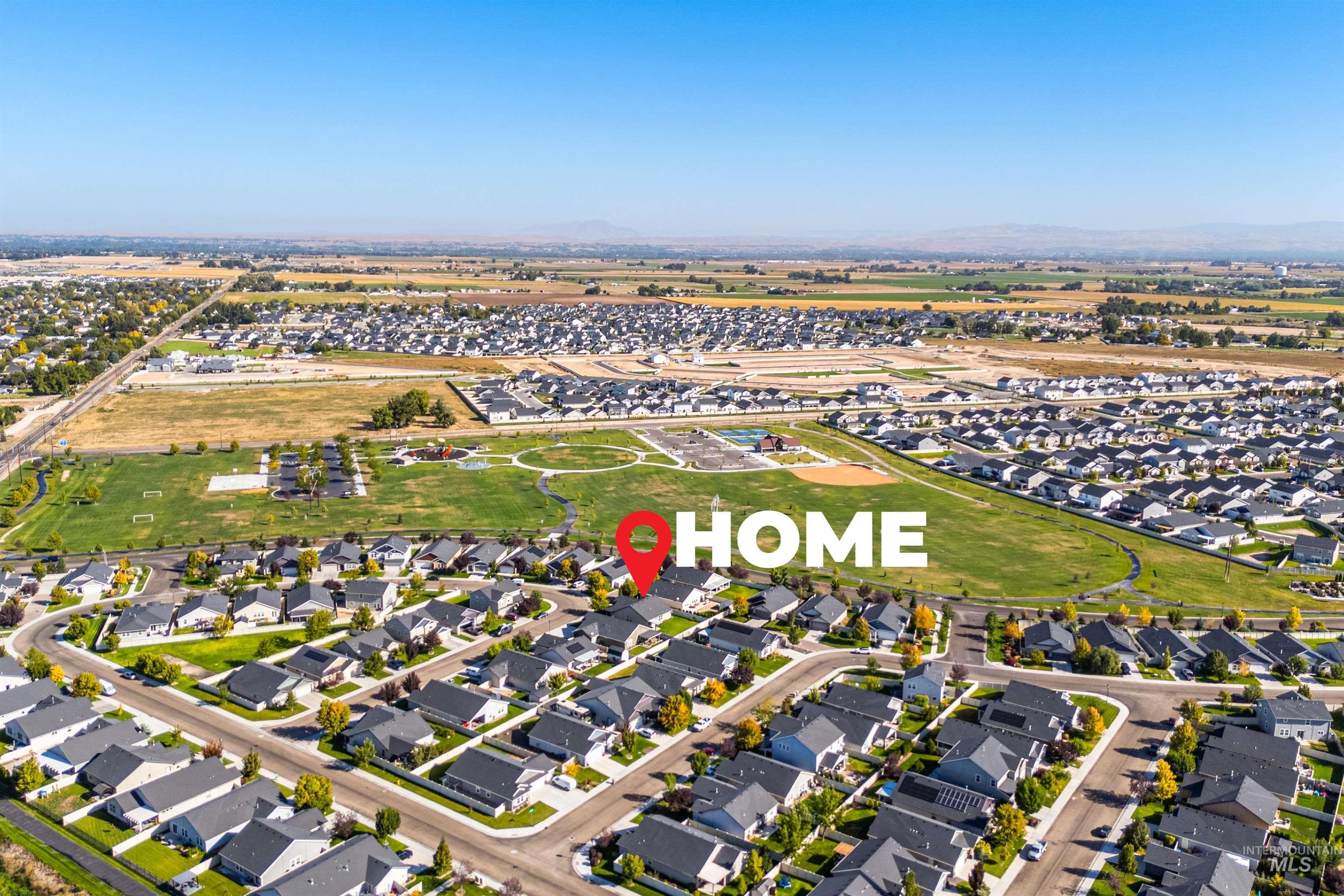 Aerial view of property and surrounding area featuring nearby suburban area and a mountainous background