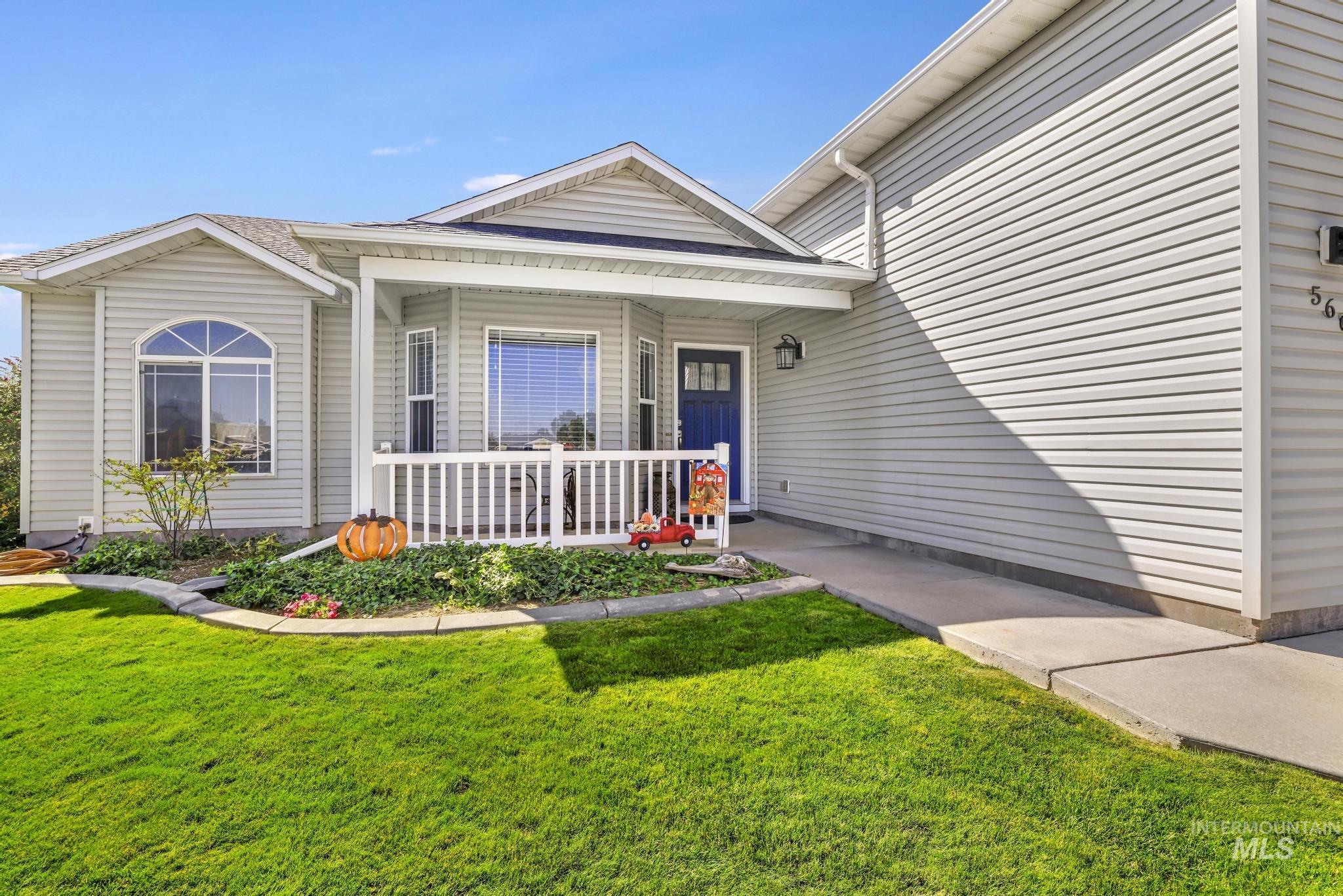 Property entrance with a porch, a yard, and a shingled roof