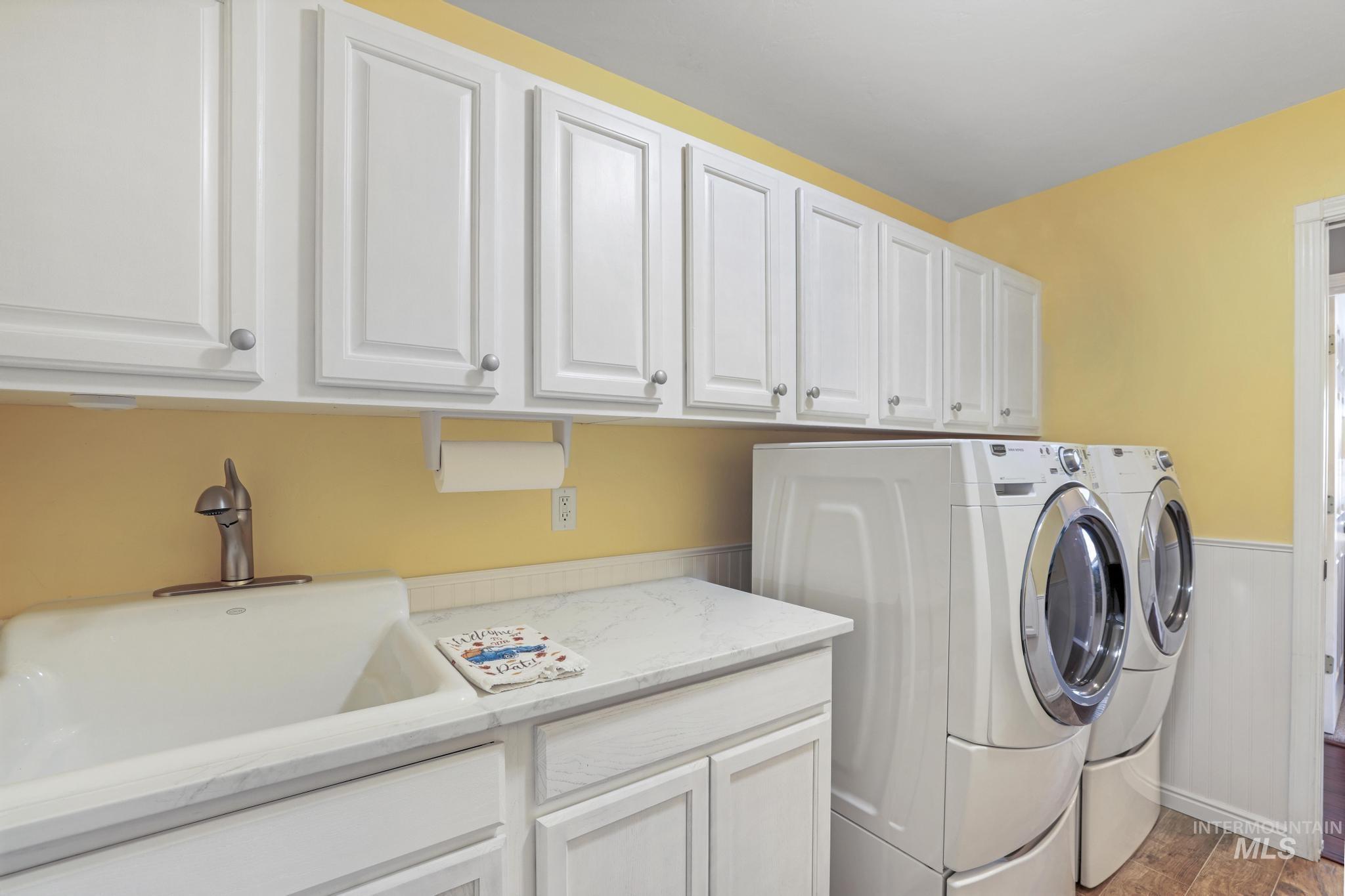 Laundry room with wainscoting, separate washer and dryer, light wood finished floors, and cabinet space