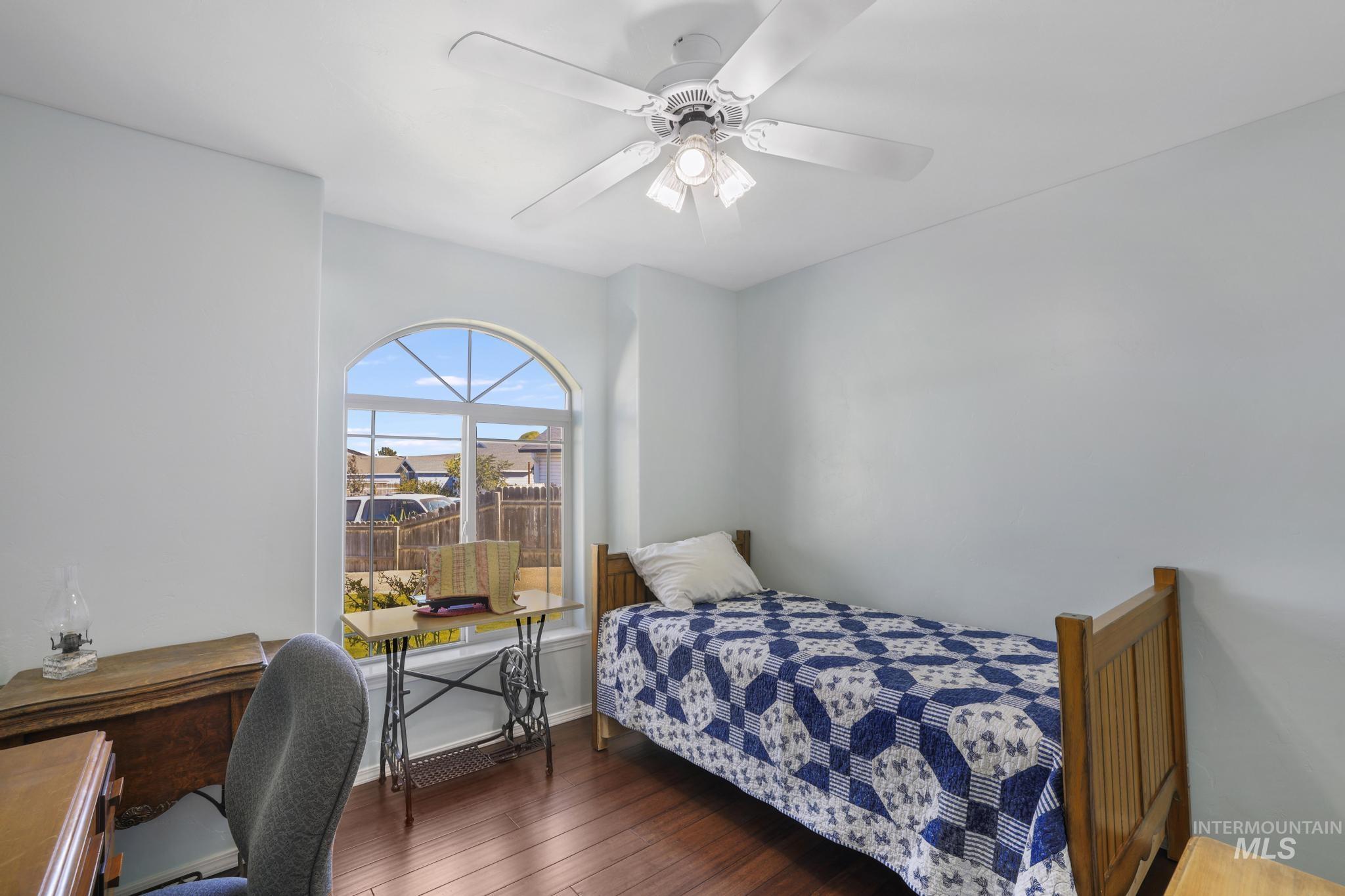 Bedroom featuring dark wood-style flooring, ceiling fan, and an office area