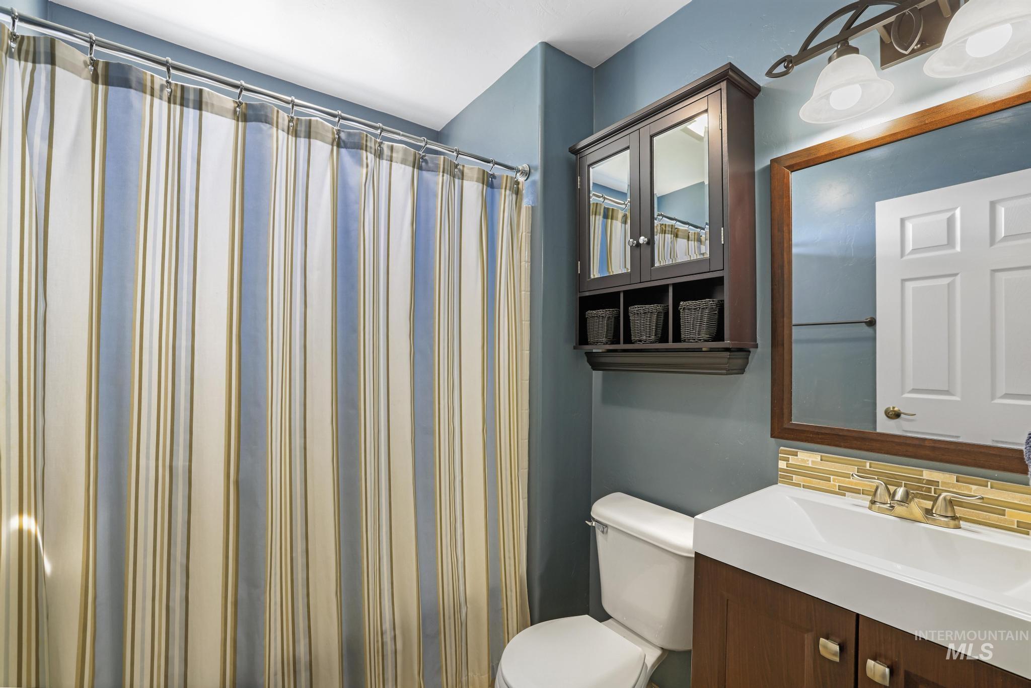 Bathroom featuring backsplash, vanity, and a shower with curtain