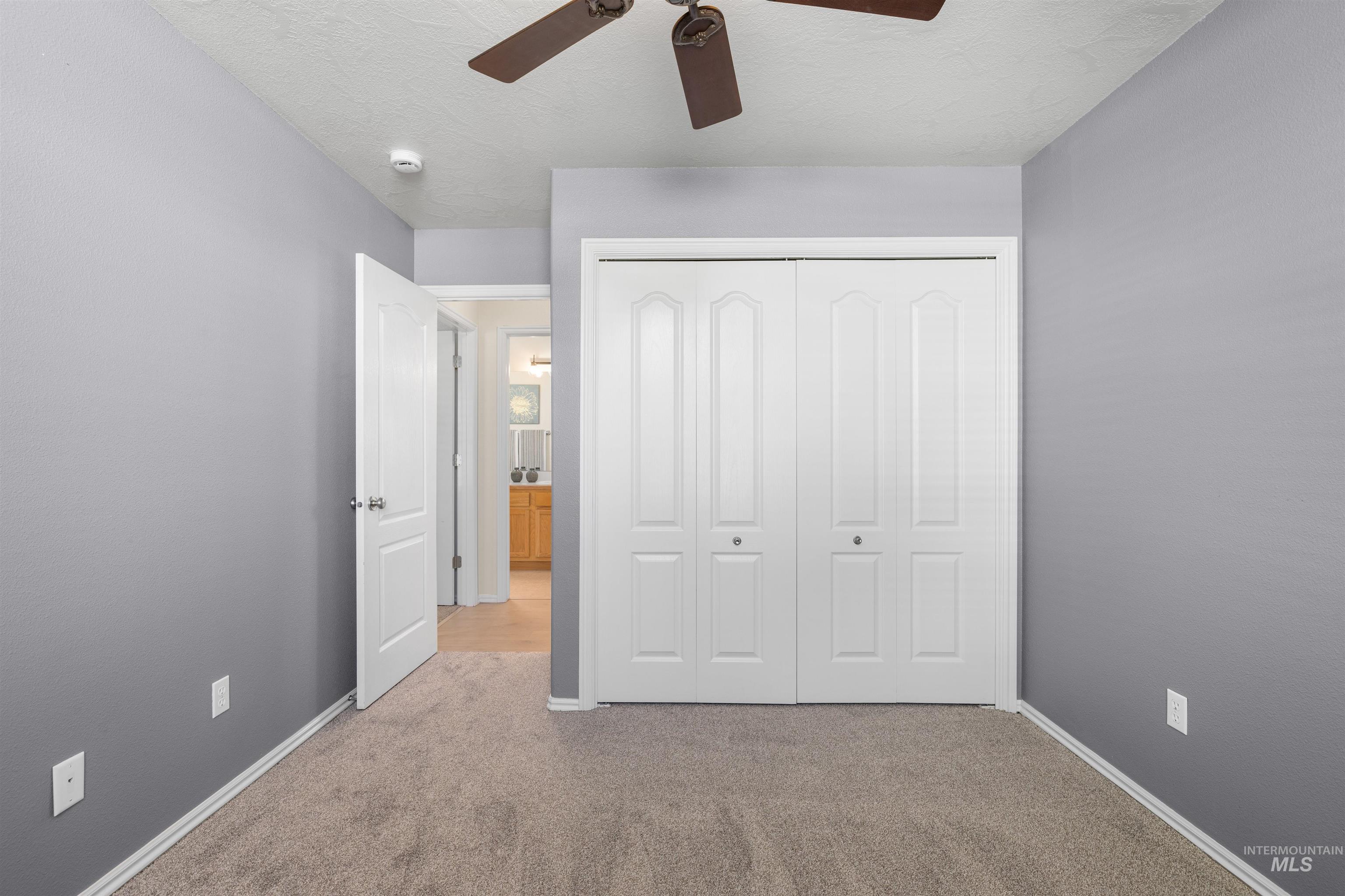 Unfurnished bedroom with carpet floors, a closet, a textured ceiling, and ceiling fan