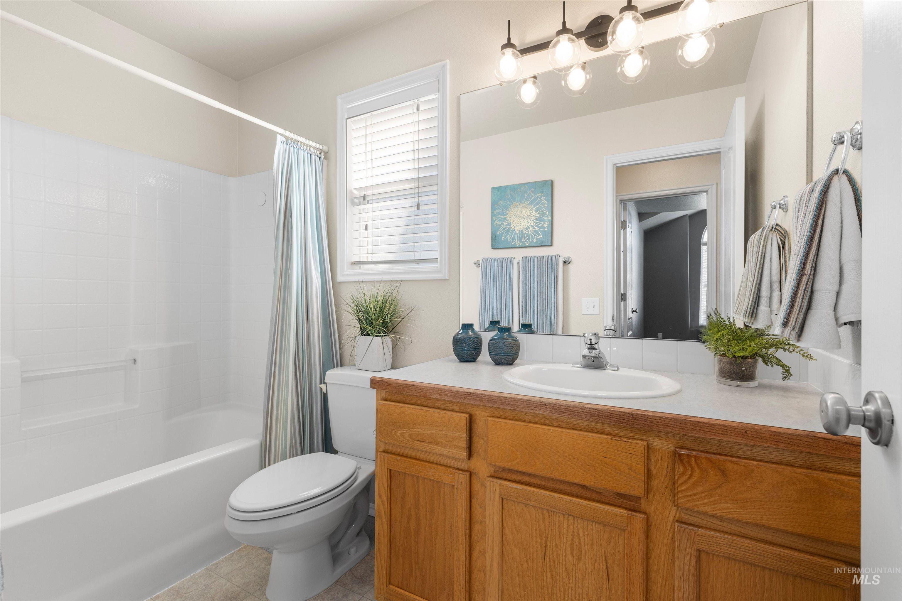 Full bath featuring shower / bath combo, vanity, and light tile patterned floors
