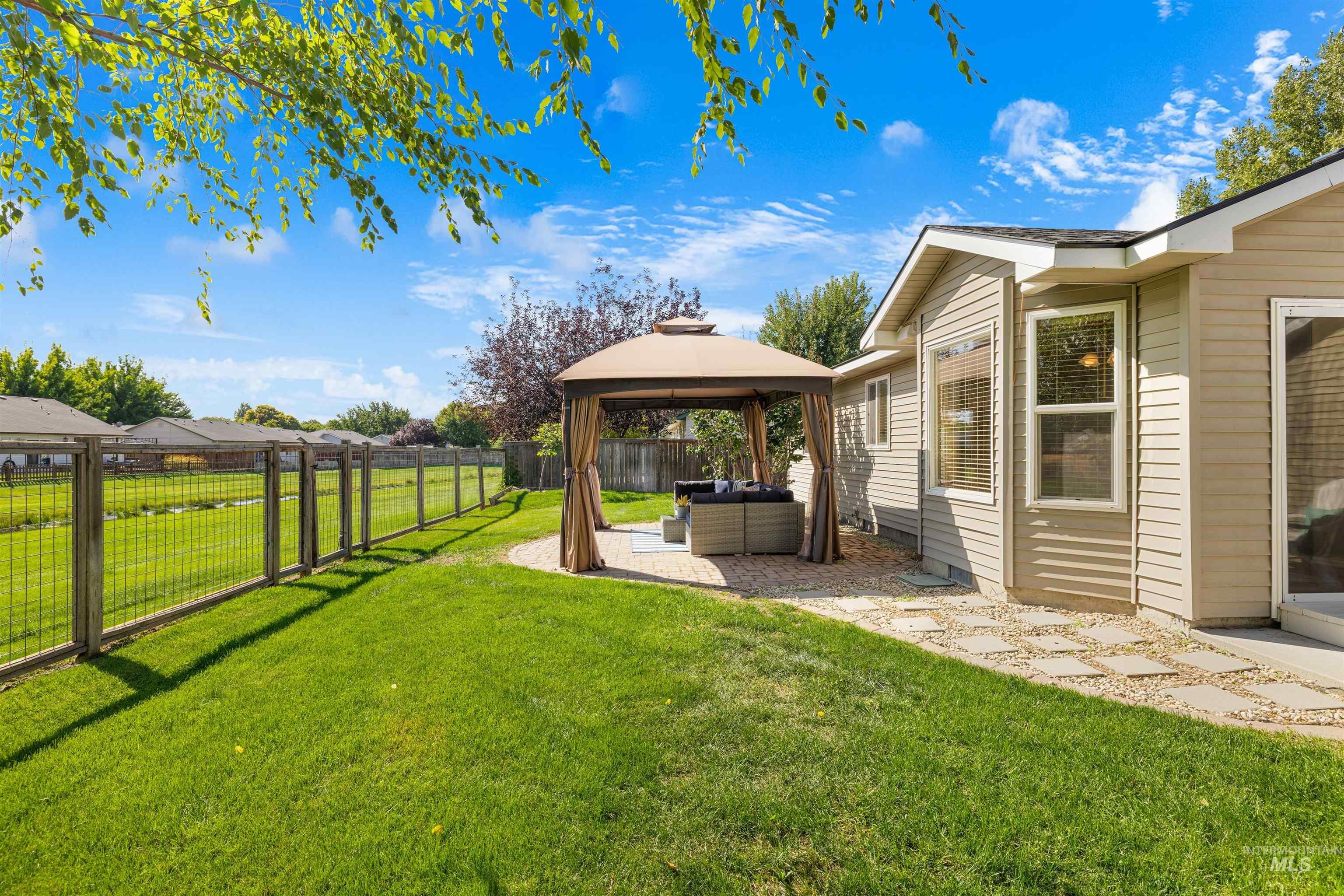 Fenced backyard featuring a gazebo, a patio area, and an outdoor hangout area