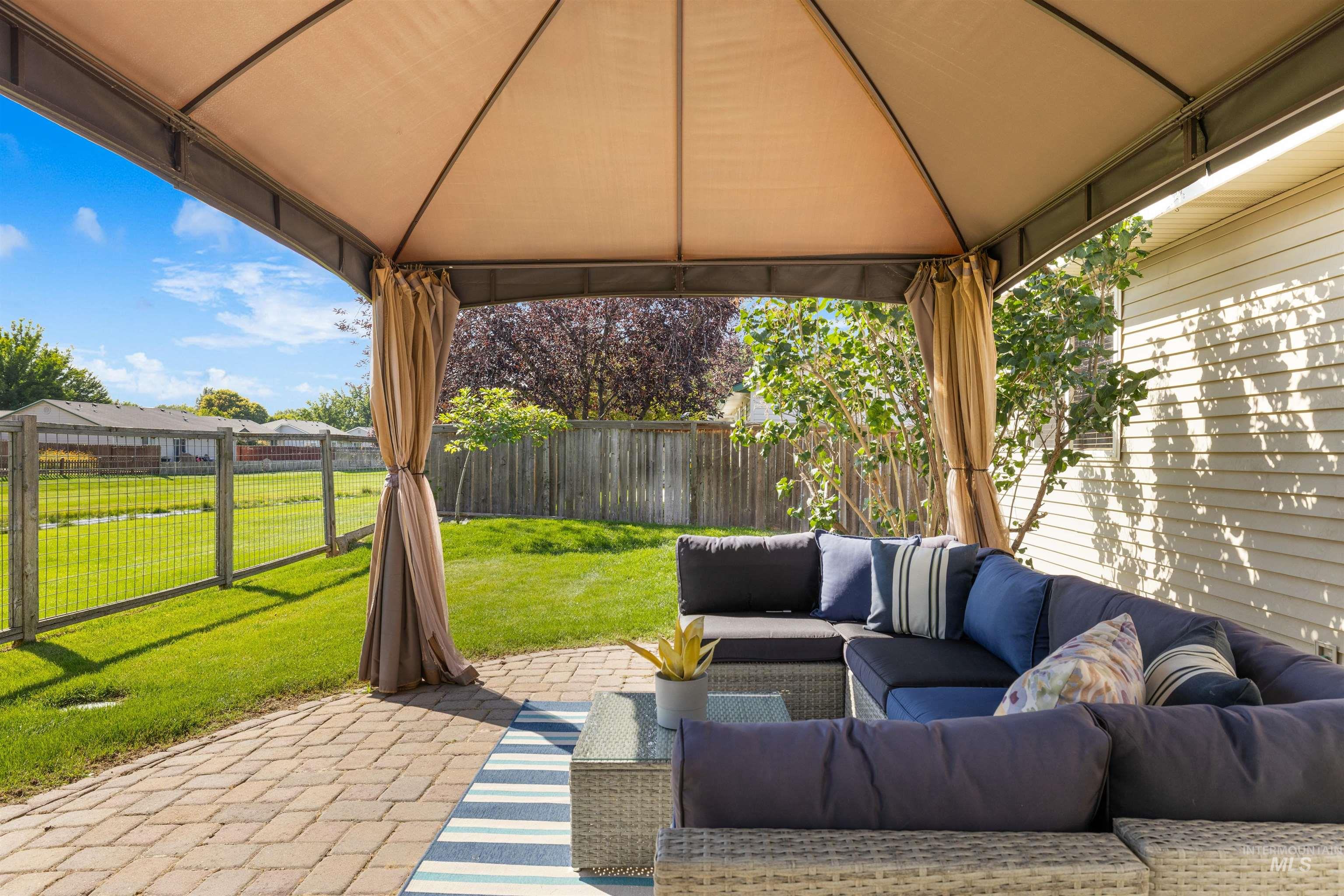 Fenced backyard with a patio, an outdoor living space, and a gazebo