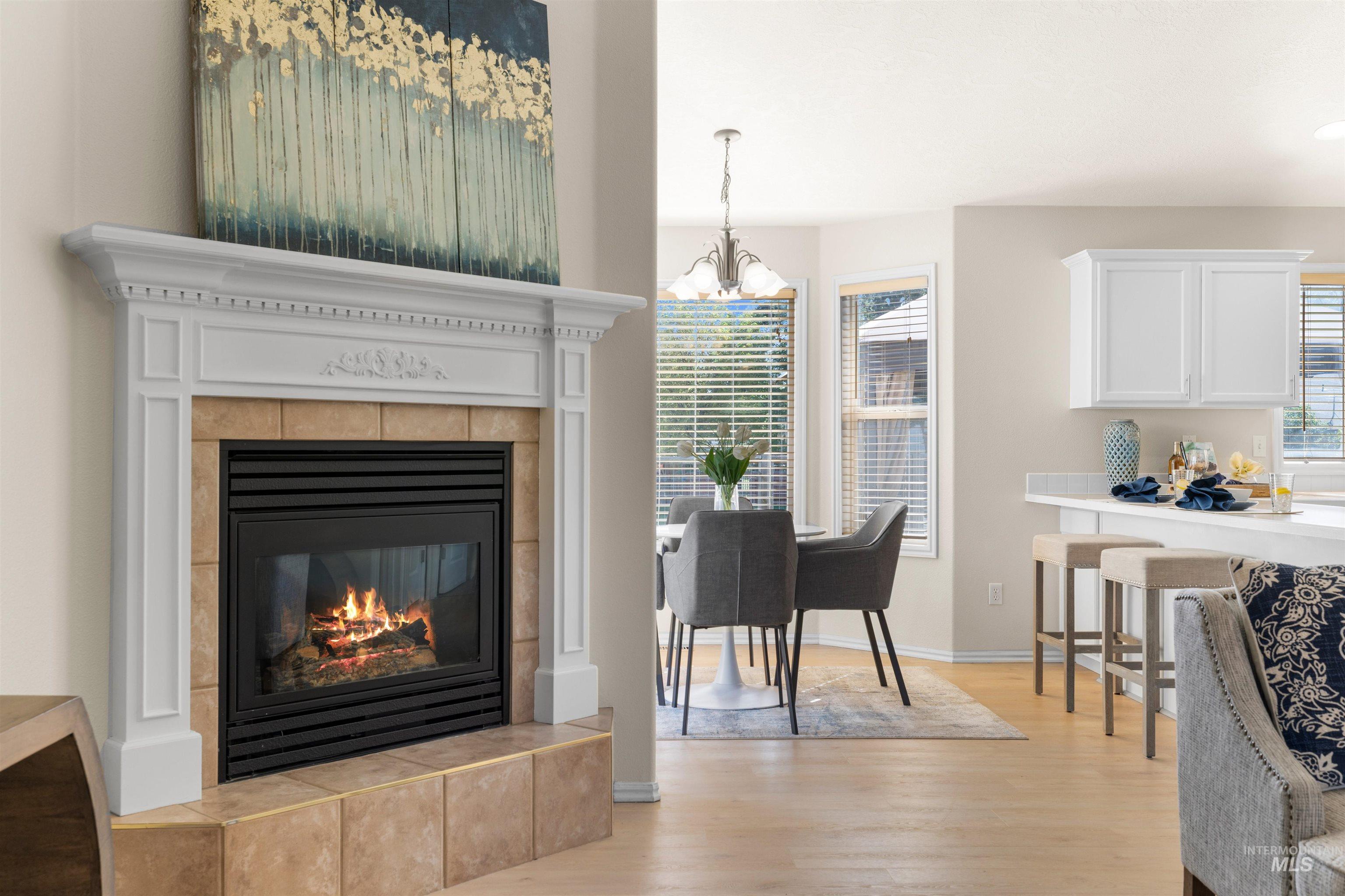 Dining room featuring light wood-type flooring, a chandelier, and a fireplace