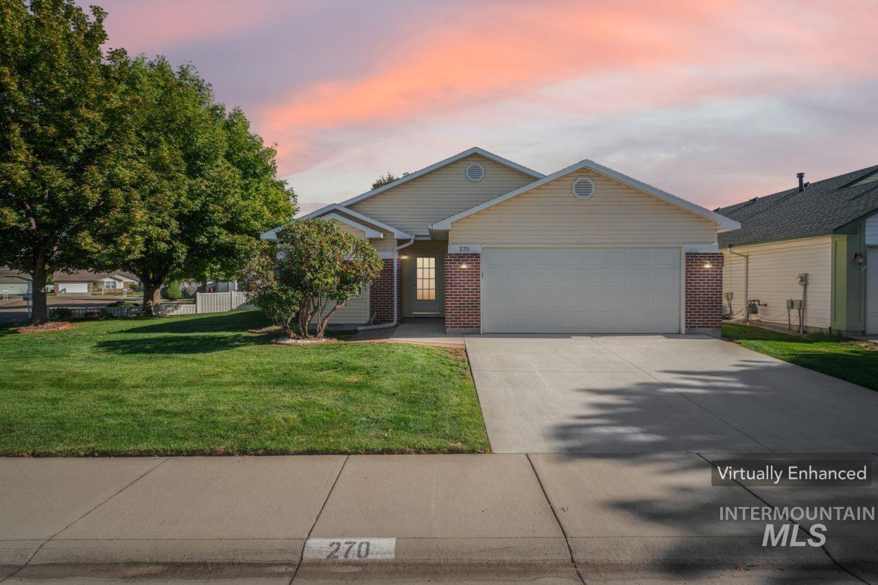 View of front of home with brick siding, driveway, an attached garage, and a yard