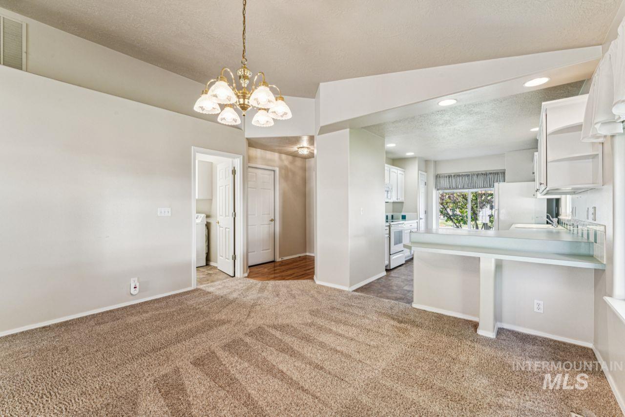 Unfurnished dining area featuring light colored carpet, a textured ceiling, a chandelier, and recessed lighting