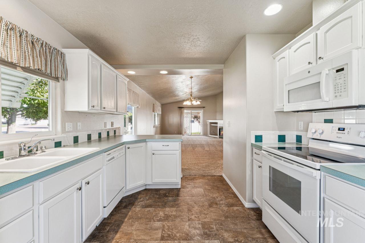 Kitchen with white appliances, plenty of natural light, backsplash, vaulted ceiling, and recessed lighting