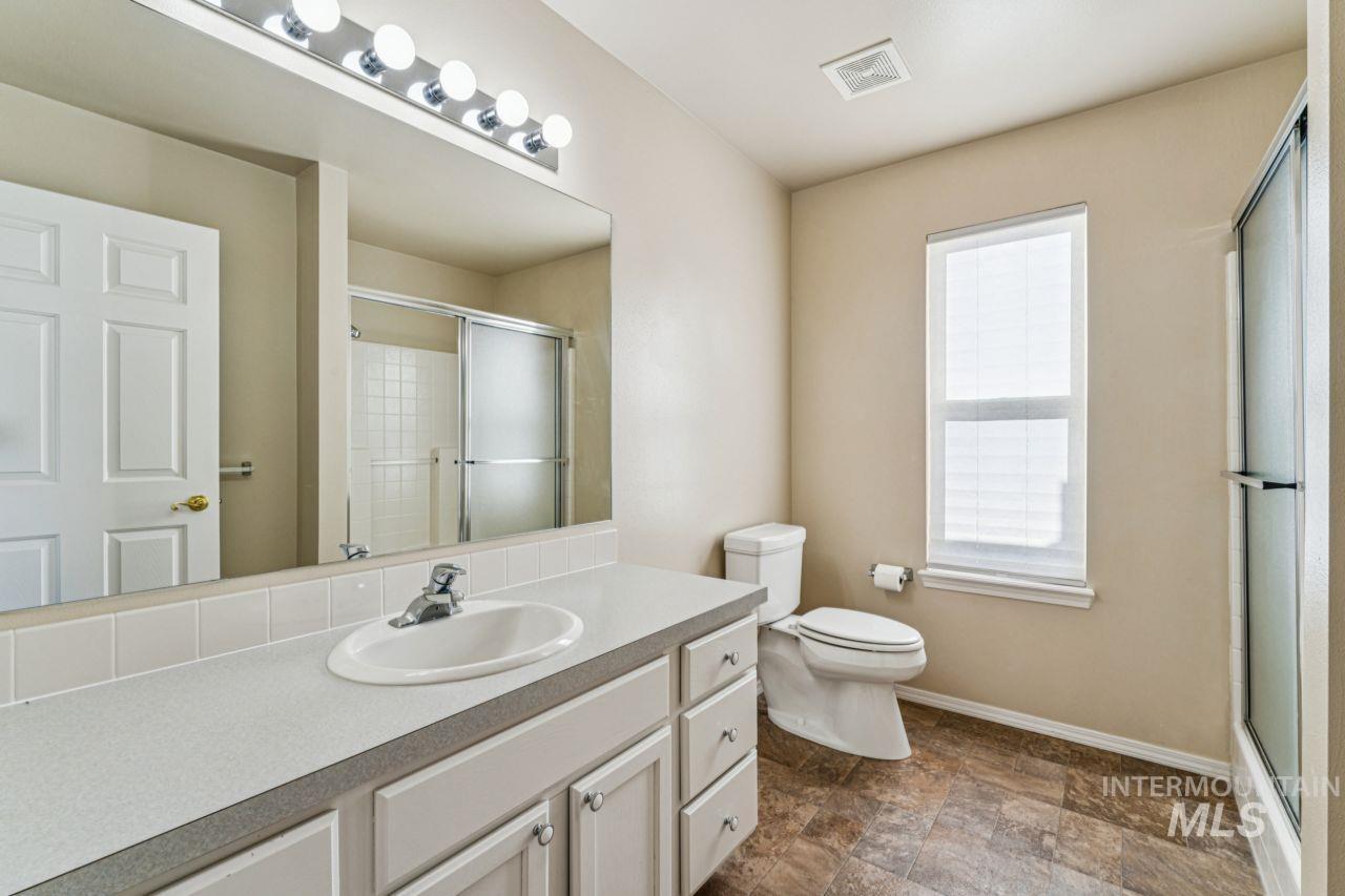 Full bathroom with vanity, a stall shower, and stone finish flooring