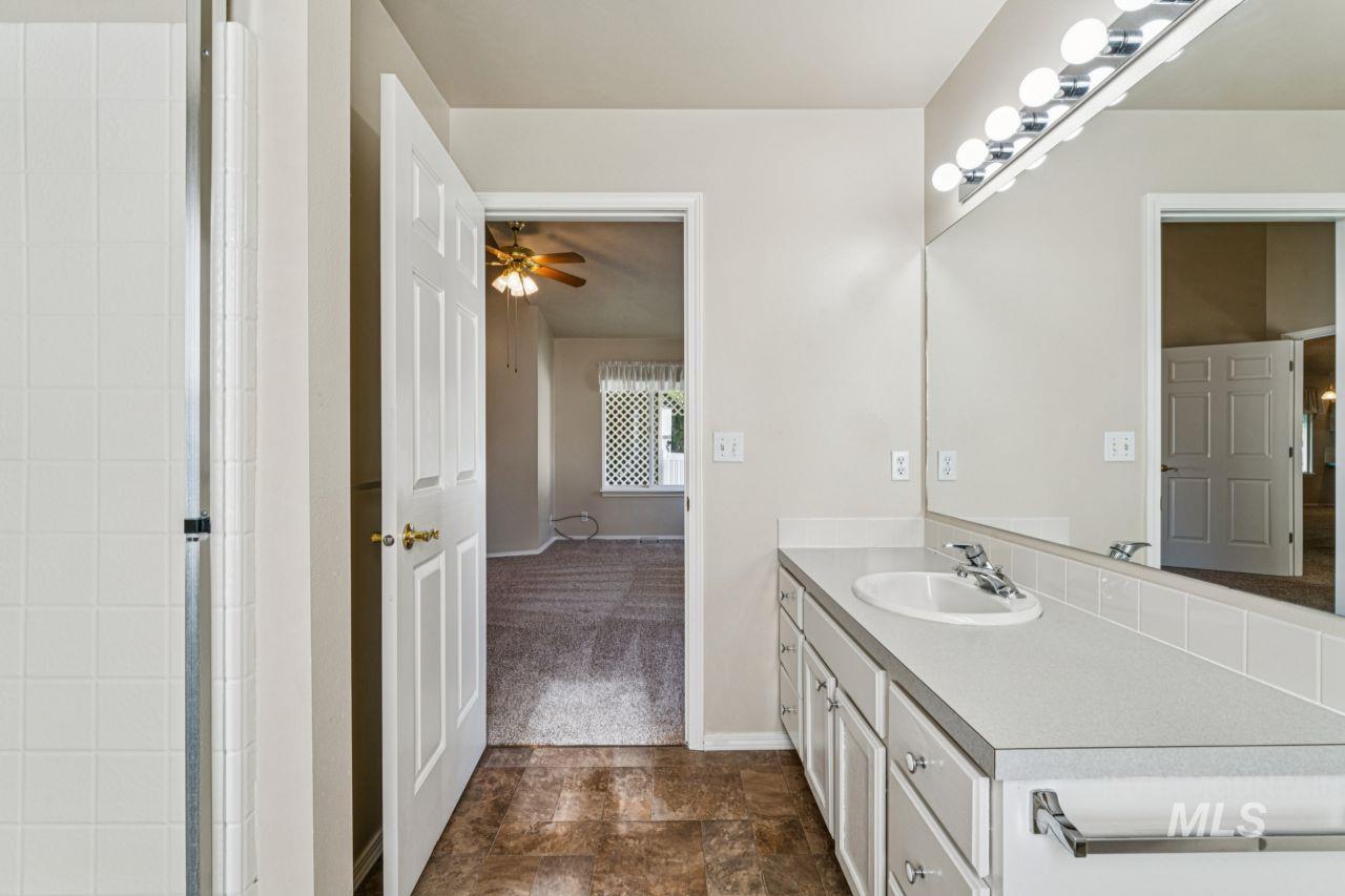 Full bathroom with vanity, a ceiling fan, stone finish floors, and a shower