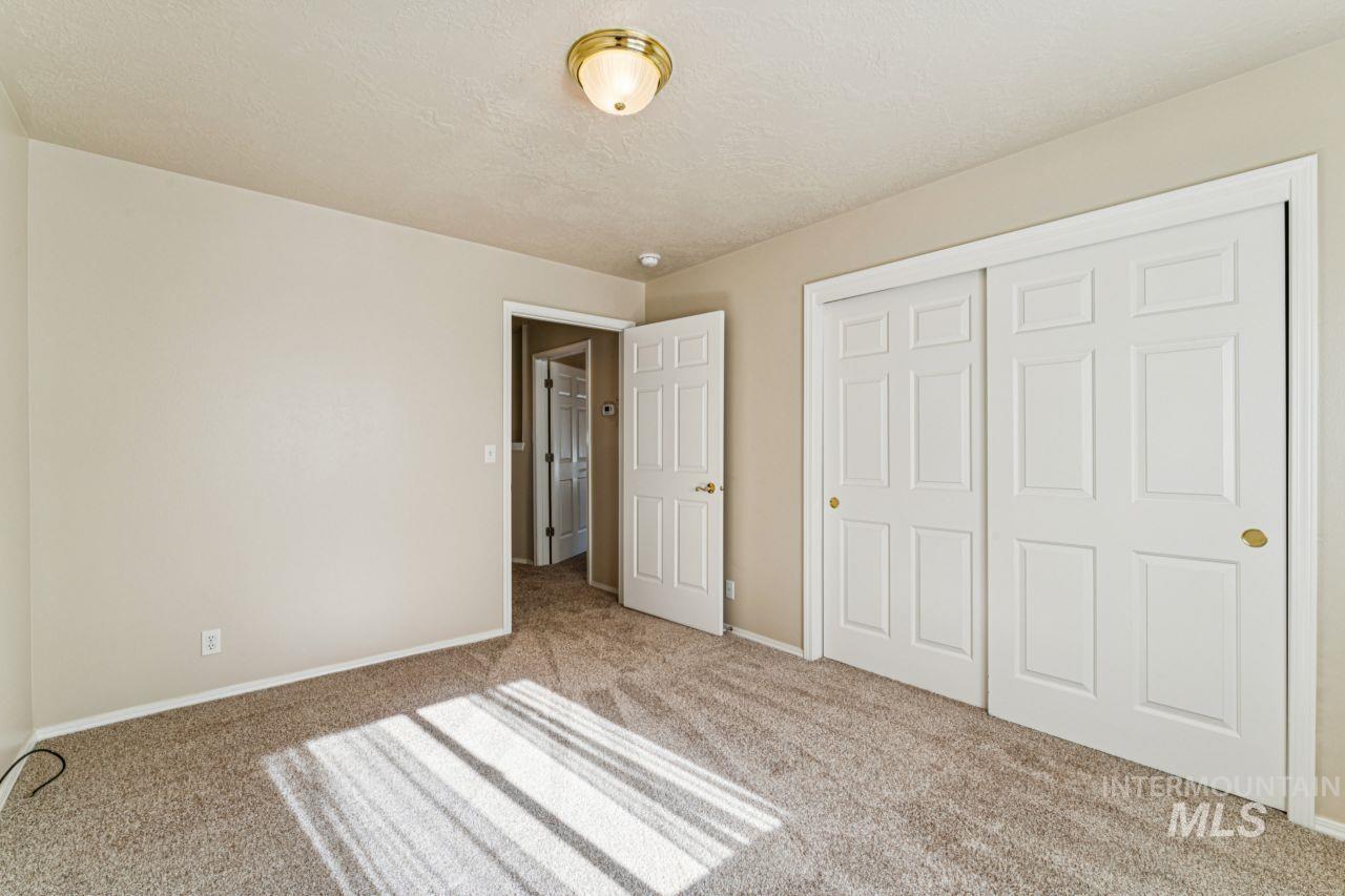 Unfurnished bedroom featuring a textured ceiling, light carpet, and a closet