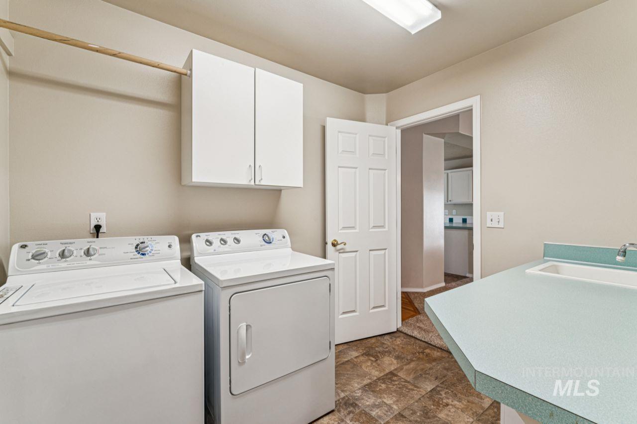 Washroom featuring cabinet space, washer and clothes dryer, and stone finish flooring