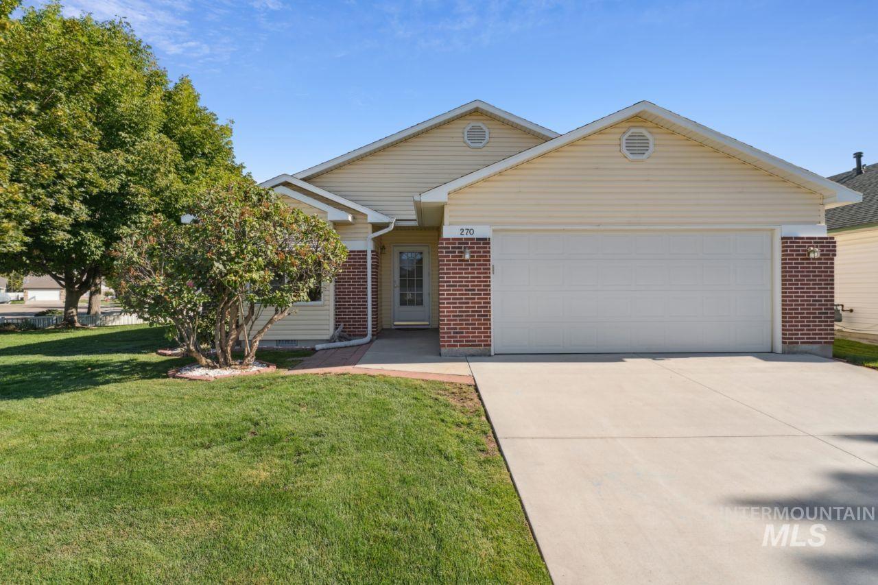 Ranch-style home featuring a garage, brick siding, driveway, and a front lawn