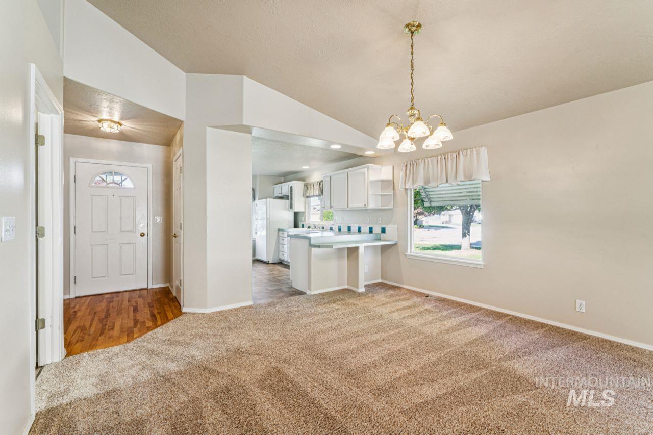 Kitchen with white cabinetry, light countertops, open shelves, light carpet, and decorative light fixtures