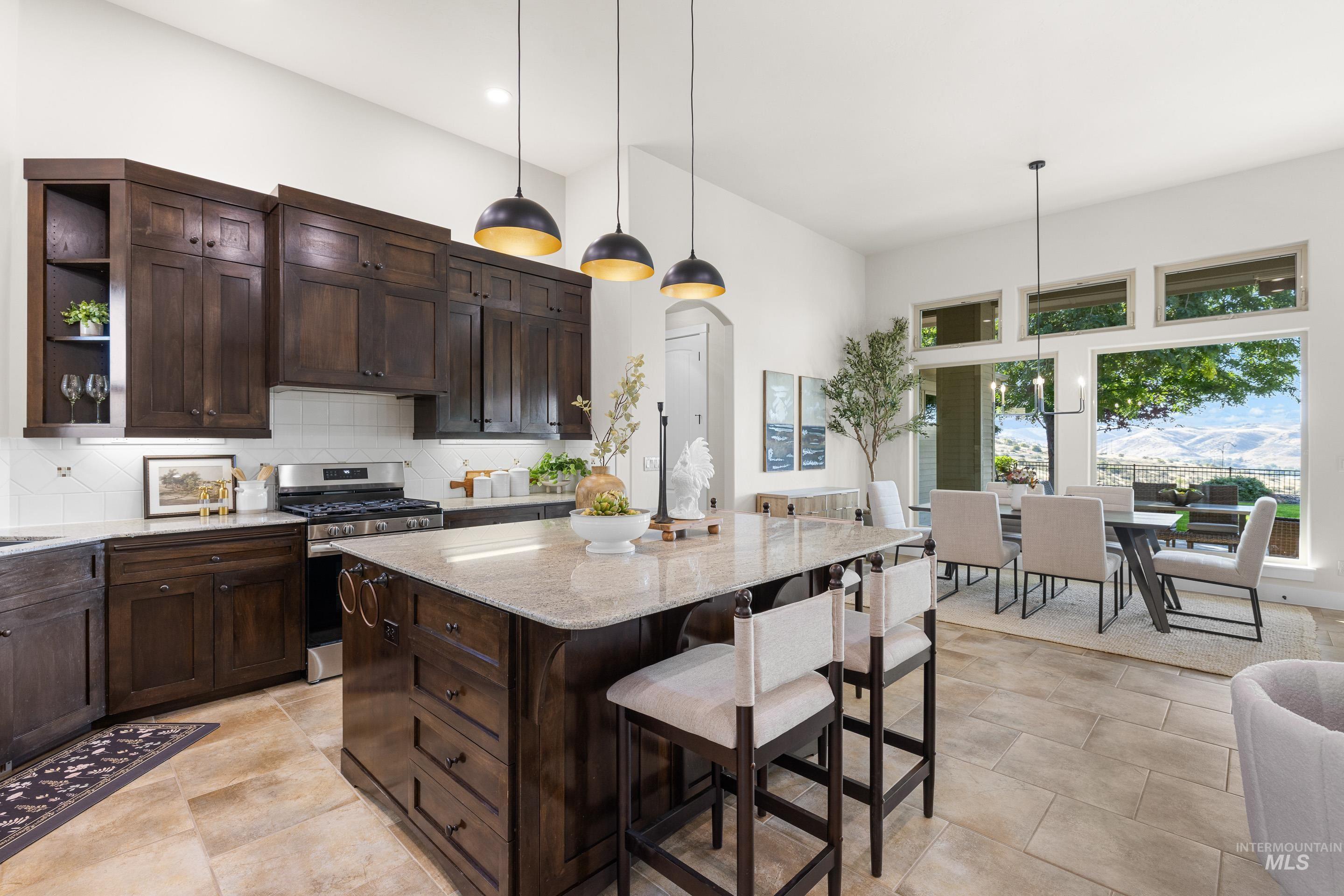 Kitchen with dark brown cabinetry, gas stove, backsplash, light stone counters, and arched walkways