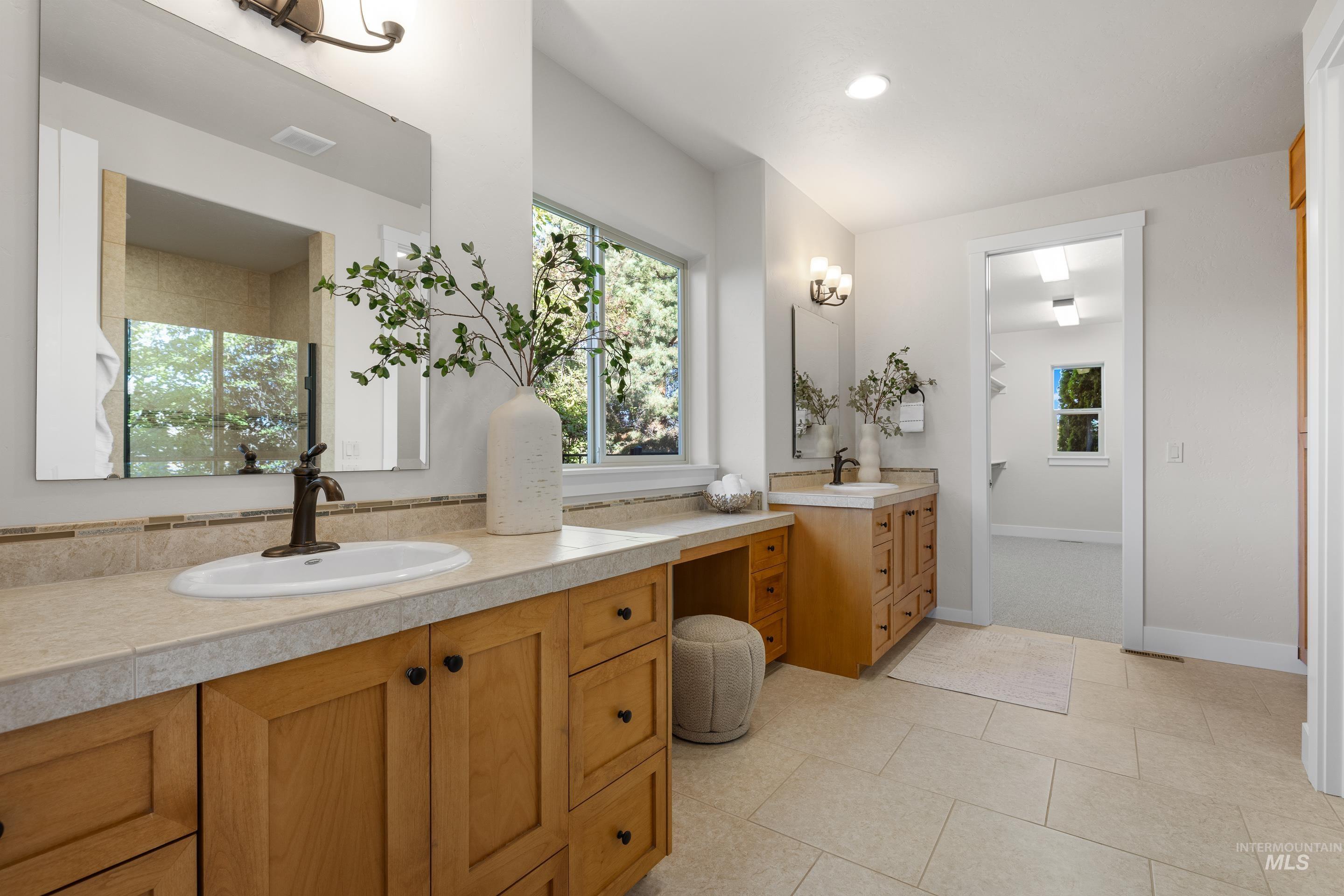 Full bathroom featuring healthy amount of natural light, two vanities, recessed lighting, and a shower