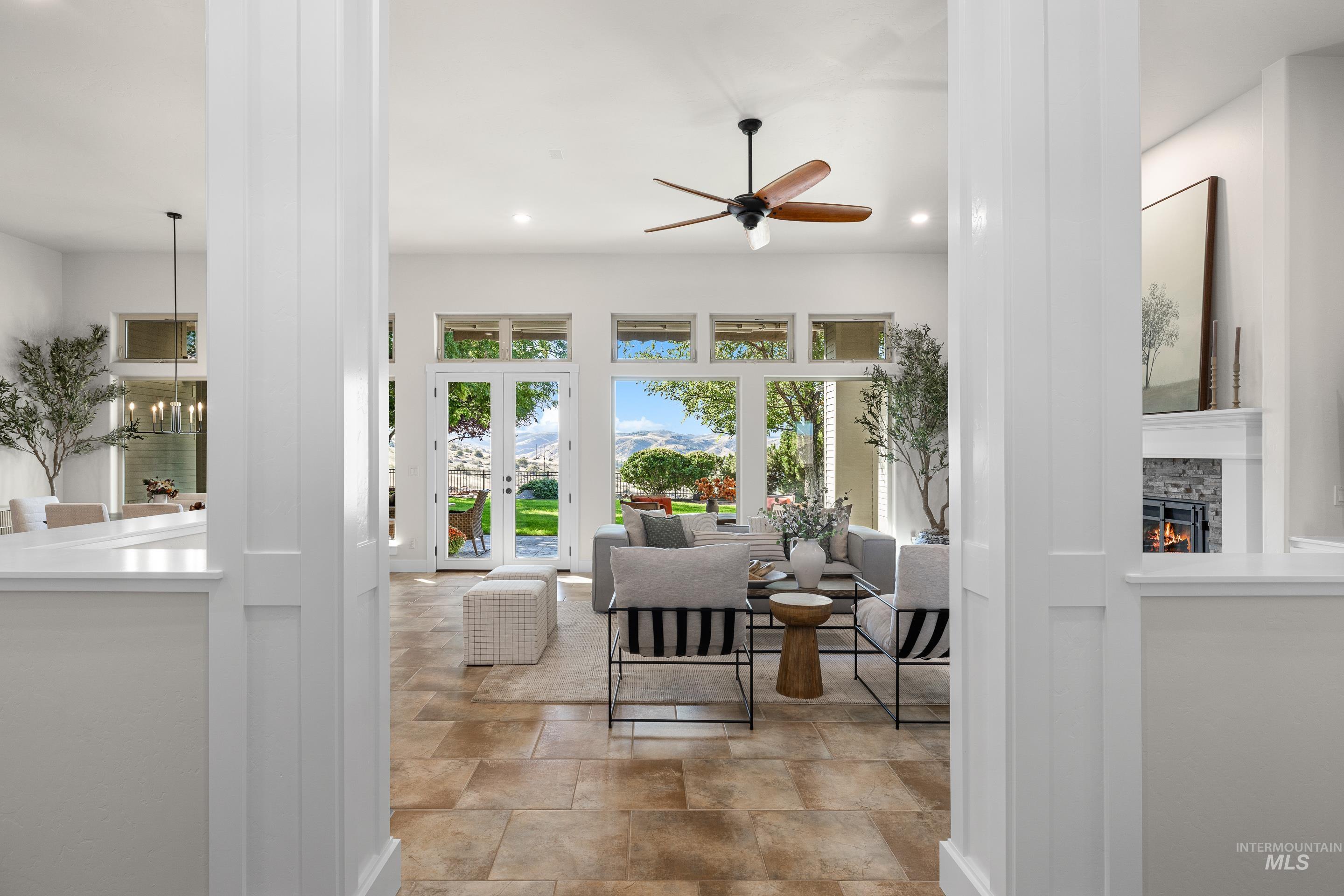 Living room with recessed lighting, ceiling fan, a fireplace, and light stone finish flooring