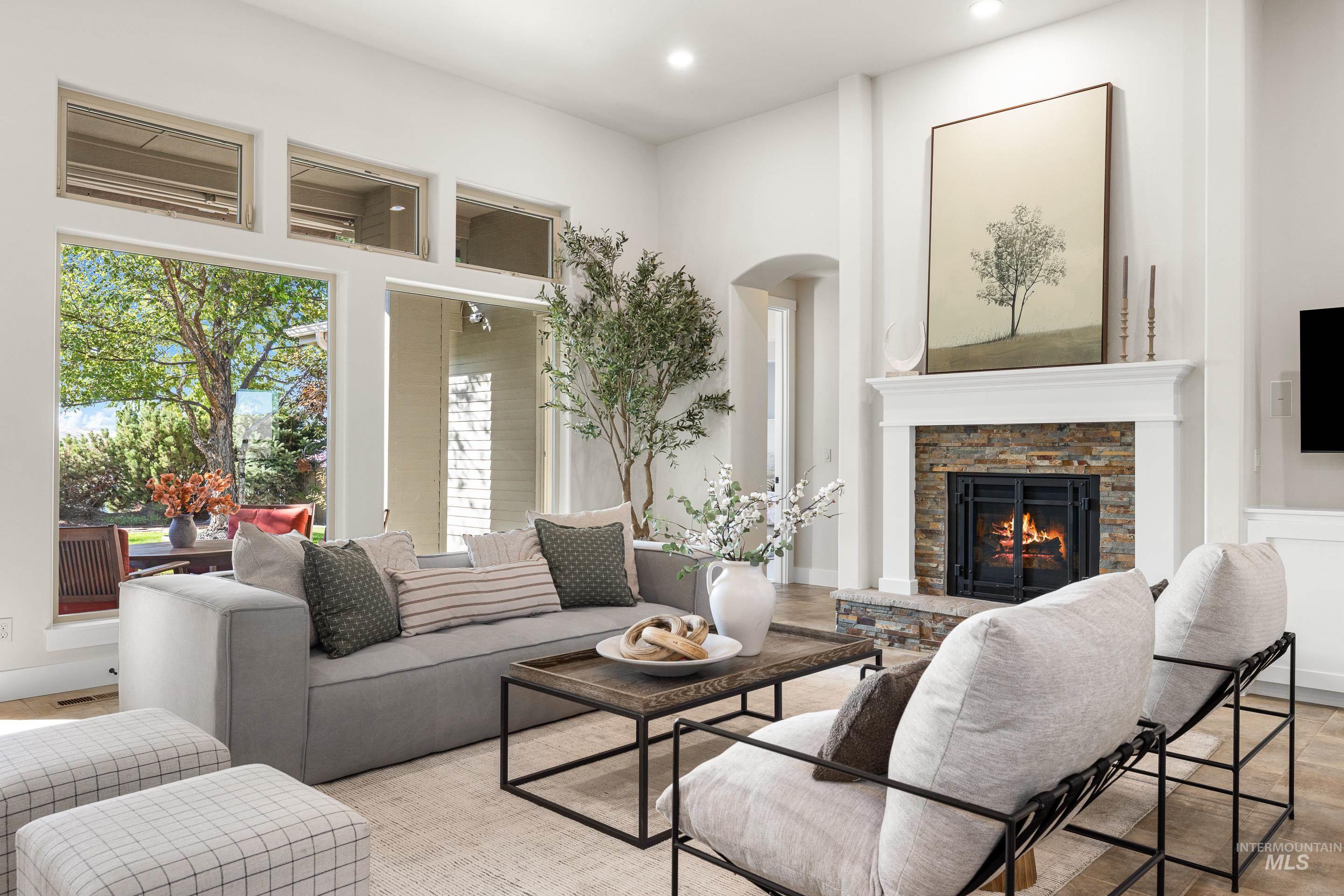 Living room with a fireplace, wood finished floors, arched walkways, recessed lighting, and a towering ceiling