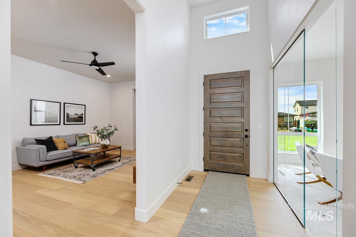 Foyer with ceiling fan, light wood finished floors, and a high ceiling