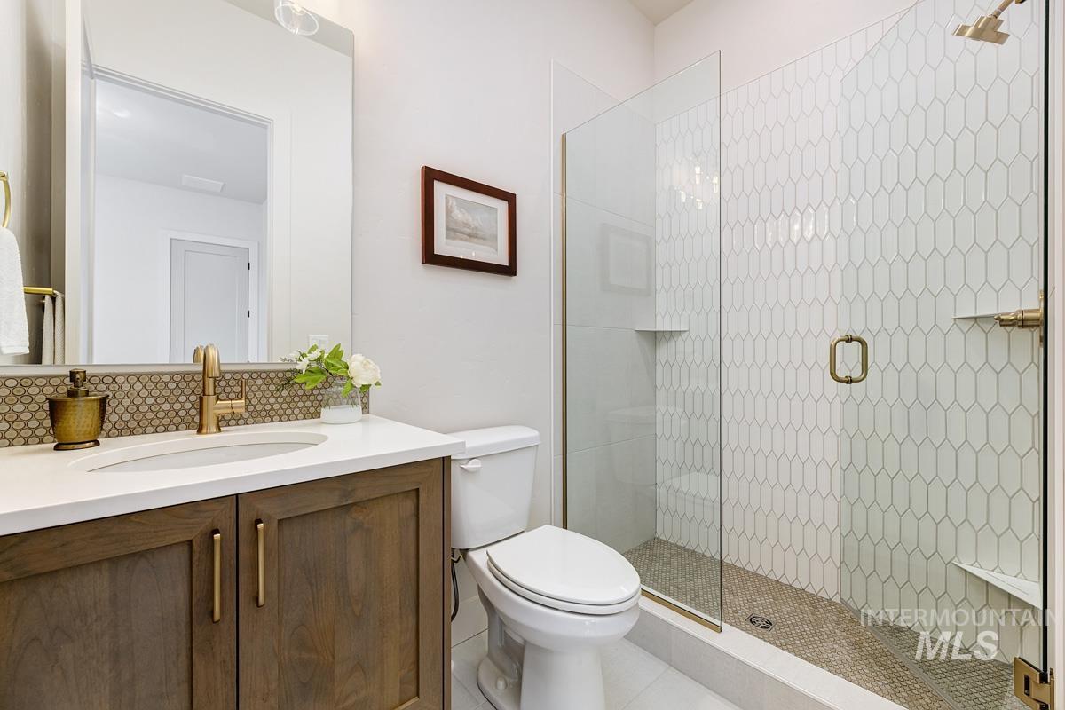 Full bathroom featuring a shower stall, vanity, and decorative backsplash