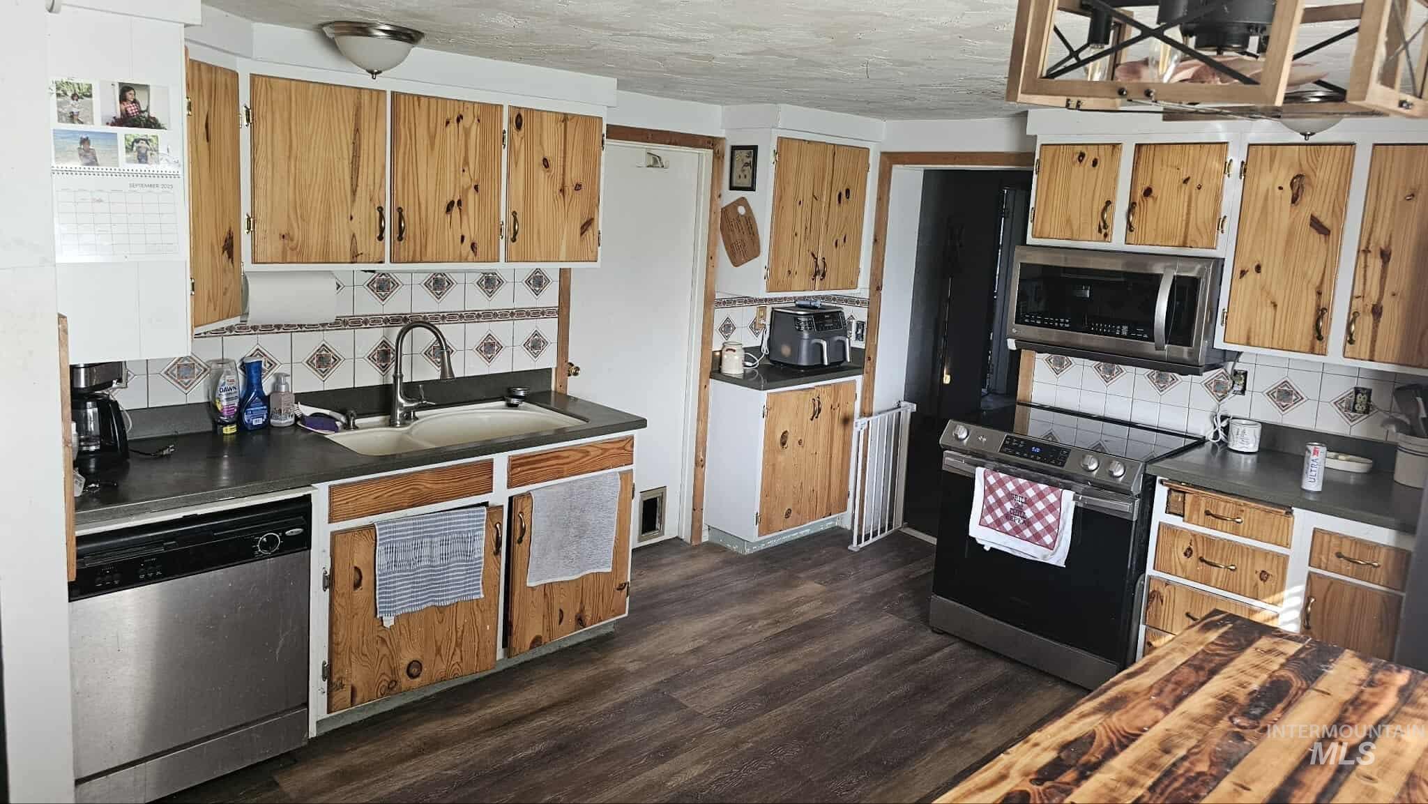 Kitchen with tasteful backsplash, dark countertops, stainless steel appliances, and a textured ceiling