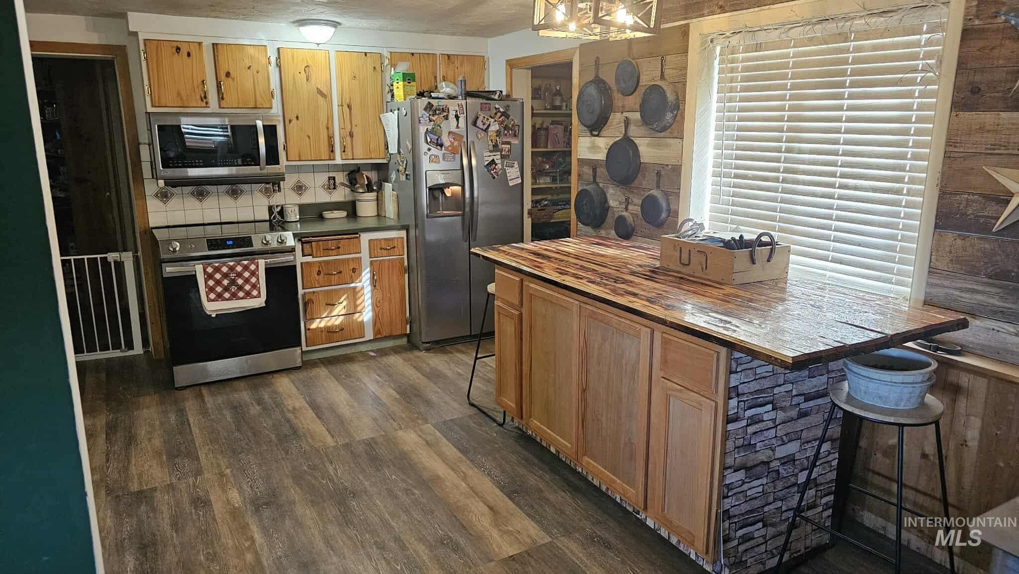 Kitchen featuring stainless steel appliances, dark wood-style floors, backsplash, brown cabinets, and butcher block countertops