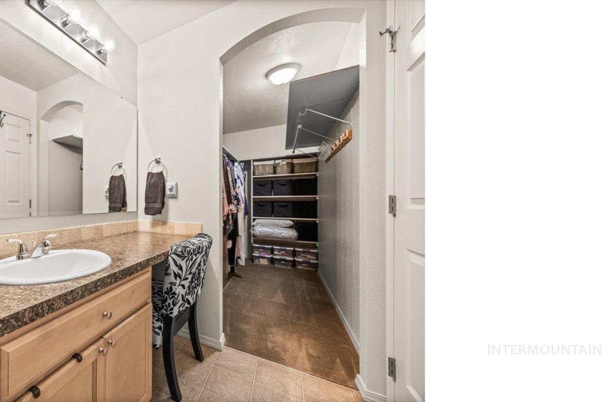 Bathroom featuring vanity, light tile patterned floors, and a walk in closet
