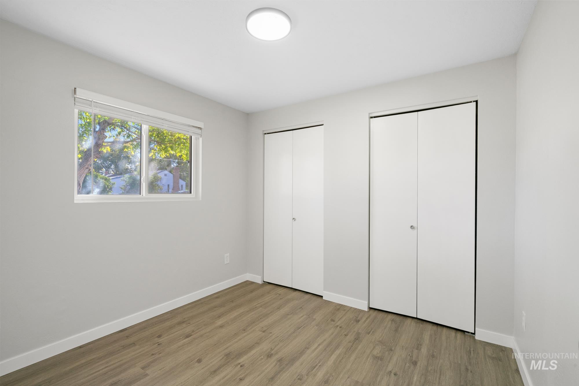 Unfurnished bedroom featuring multiple closets and wood finished floors