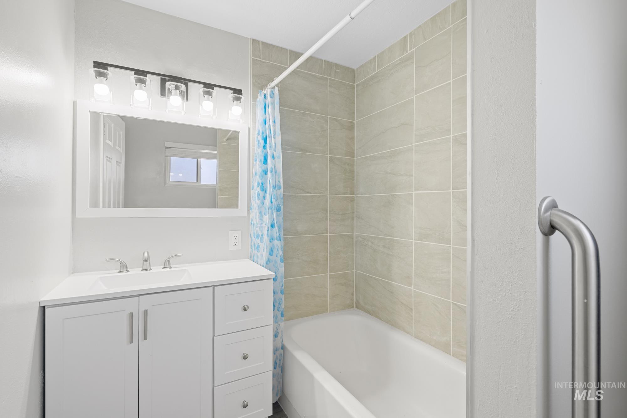 Bathroom featuring shower / bathtub combination with curtain and vanity