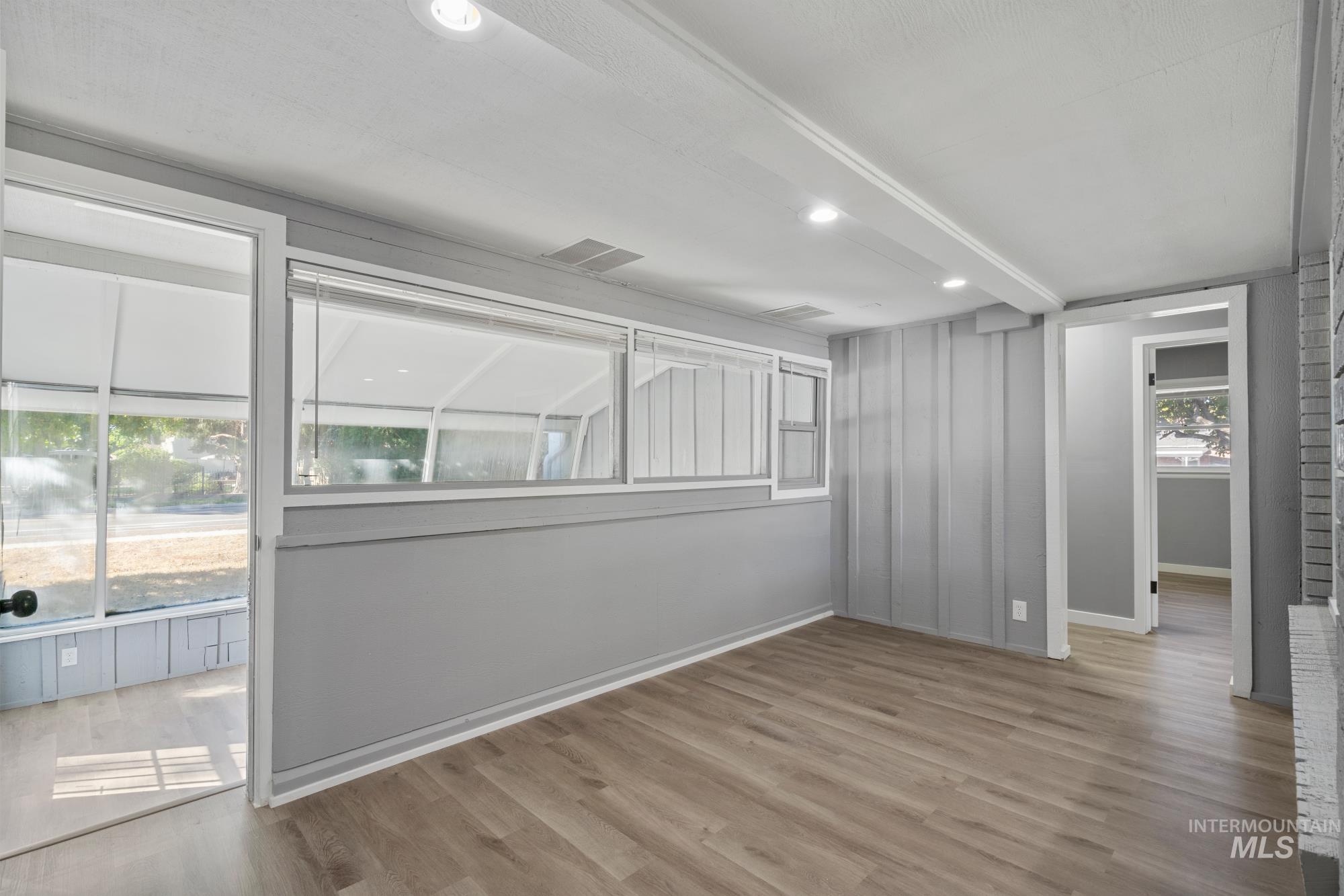 Empty room with light wood-style flooring, beamed ceiling, and recessed lighting