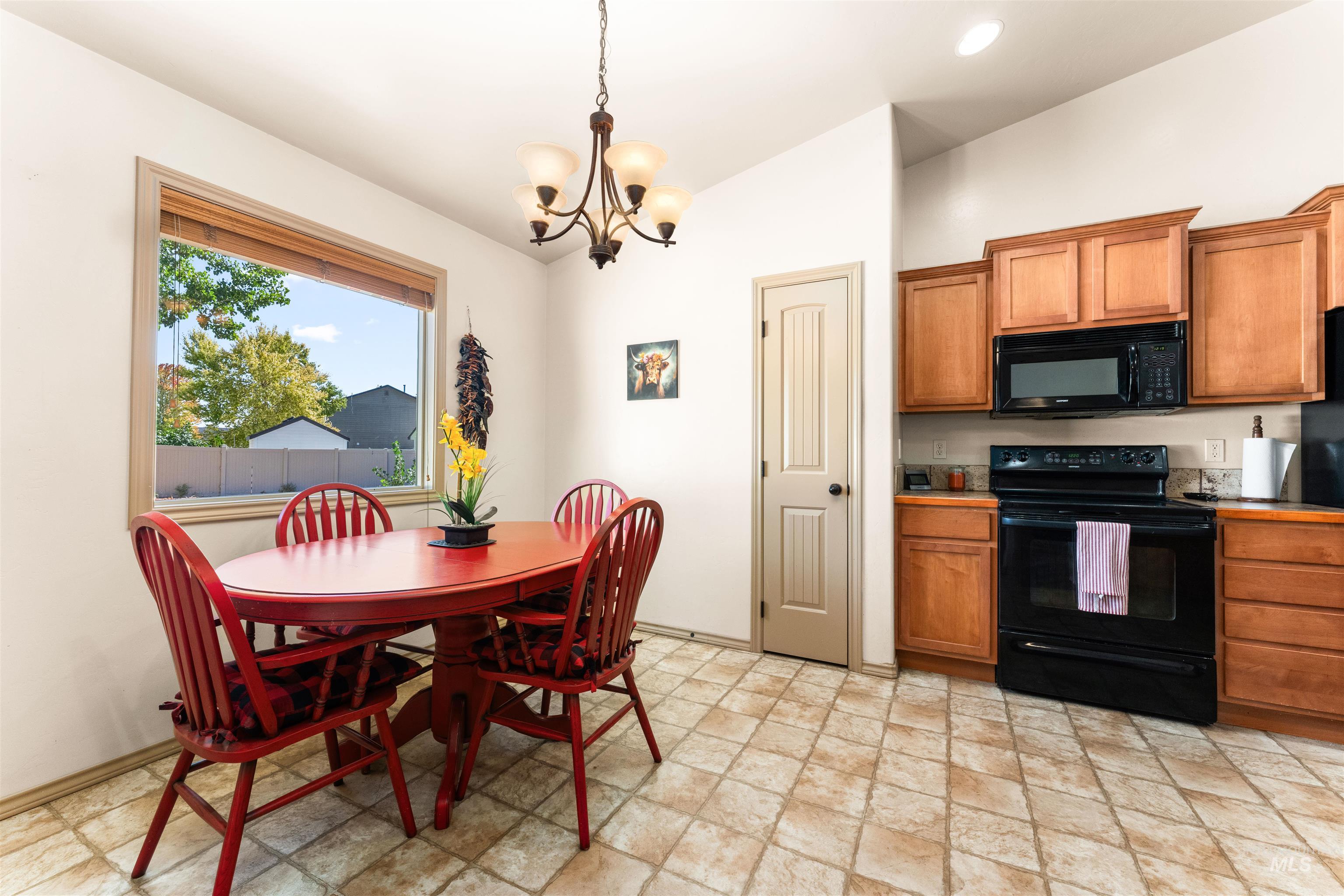 Kitchen featuring black appliances, brown cabinetry, a chandelier, pendant lighting, and lofted ceiling