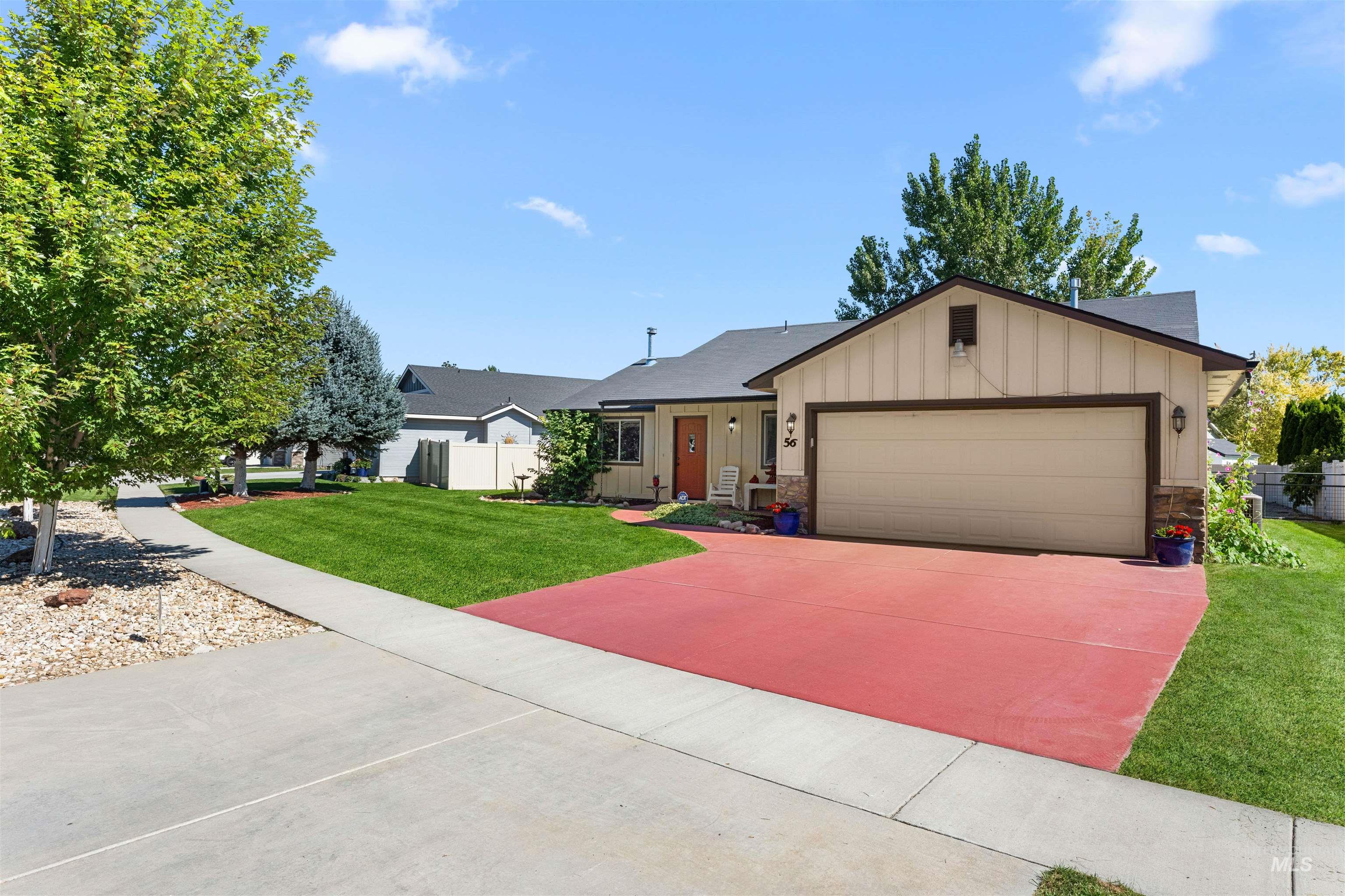 Ranch-style home with board and batten siding, a garage, driveway, and stone siding