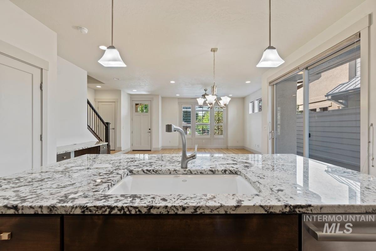 Kitchen featuring light stone countertops, recessed lighting, dark brown cabinetry, decorative light fixtures, and light wood-style flooring