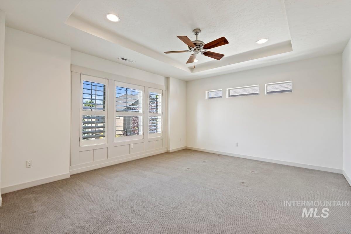 Unfurnished room featuring a tray ceiling, light carpet, ceiling fan, and recessed lighting