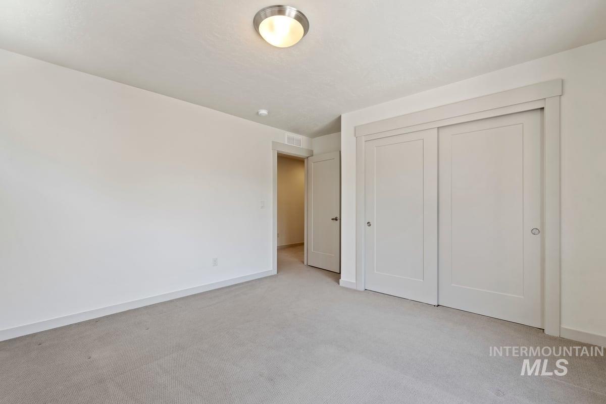 Unfurnished bedroom with light carpet and a closet