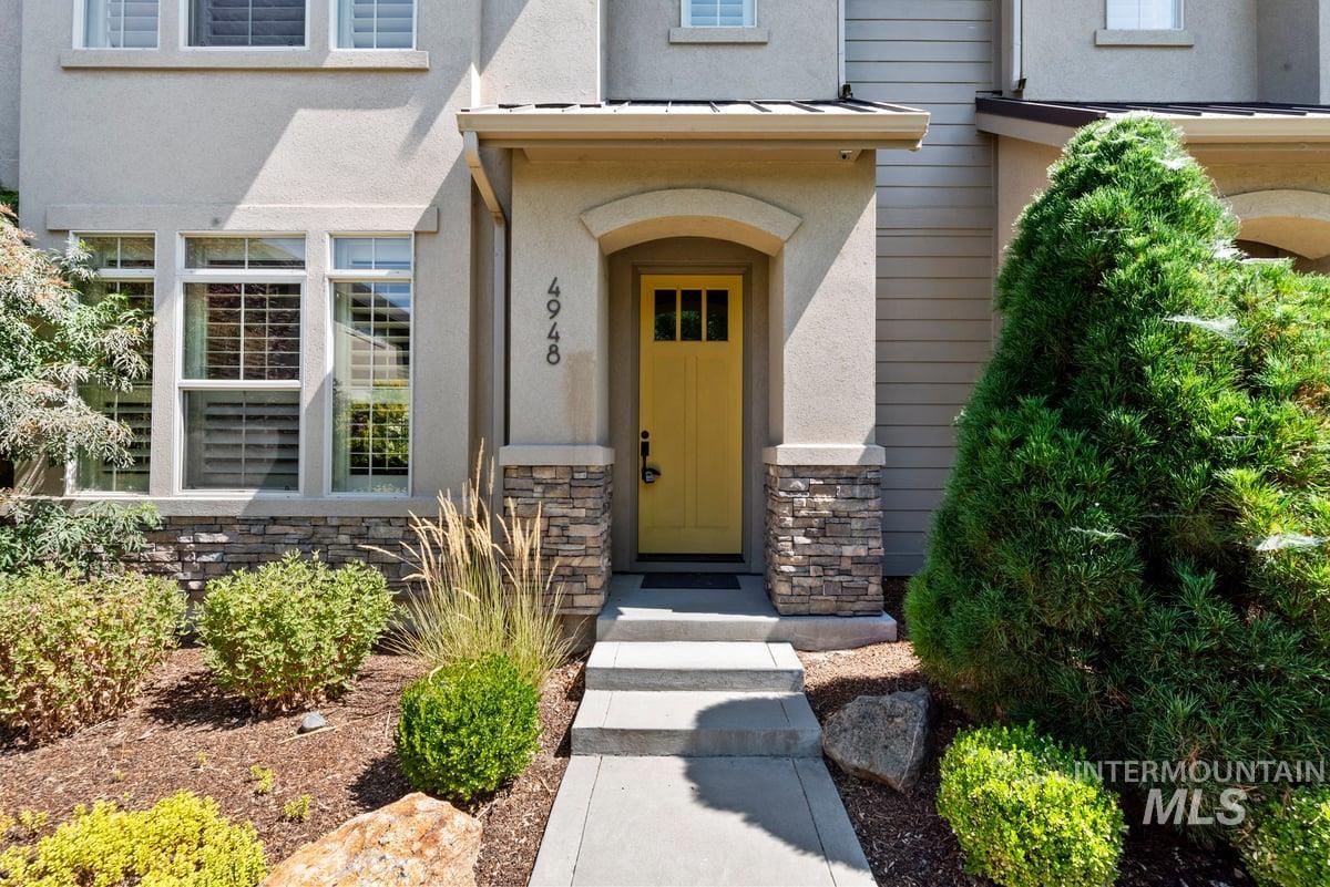 Doorway to property featuring stone siding and stucco siding