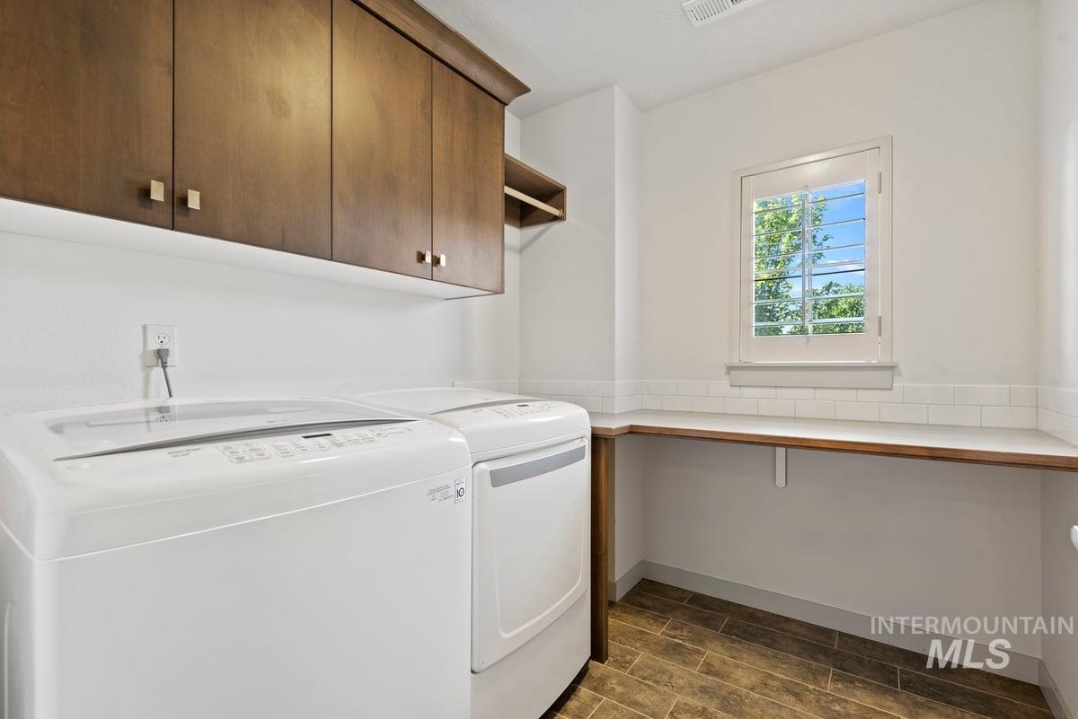 Washroom with washing machine and dryer, wood finish floors, and cabinet space