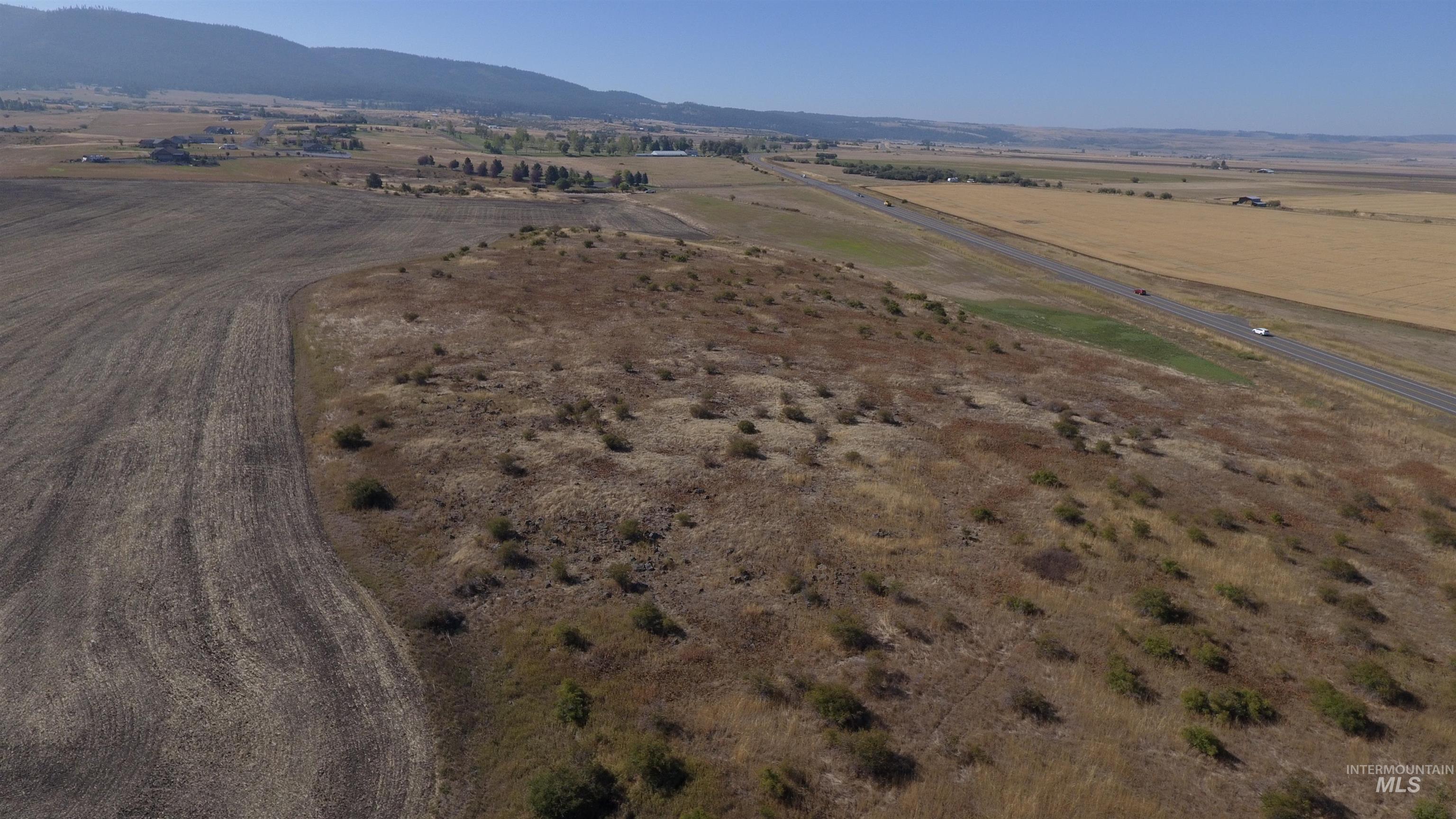 Aerial view of property and surrounding area featuring rural landscape and a mountainous background