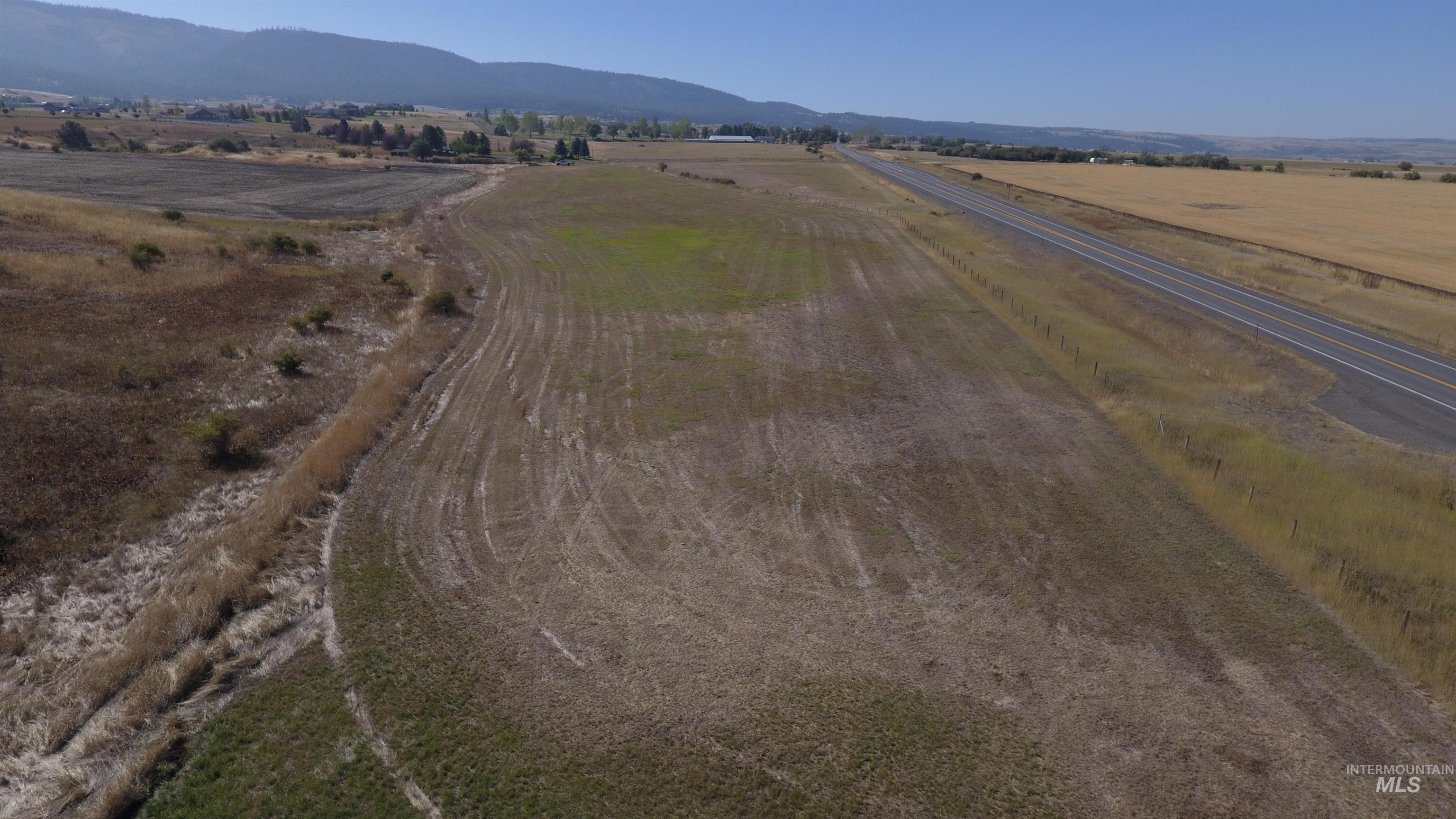 Aerial view of property and surrounding area featuring rural landscape and a mountain backdrop