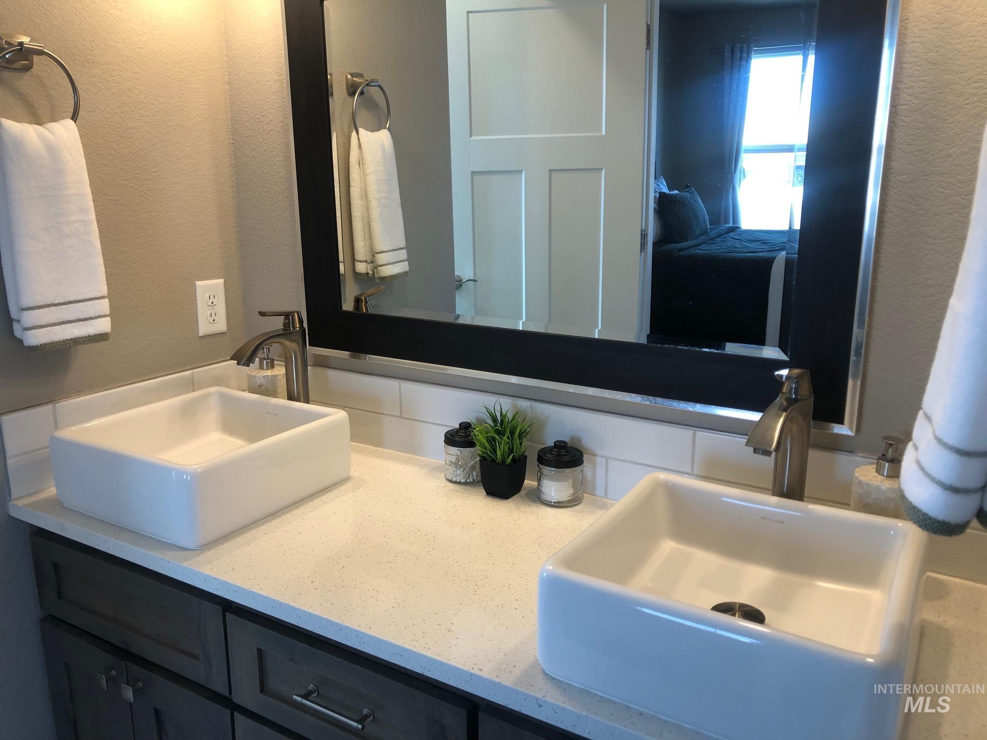Full bath featuring a textured wall and double vanity