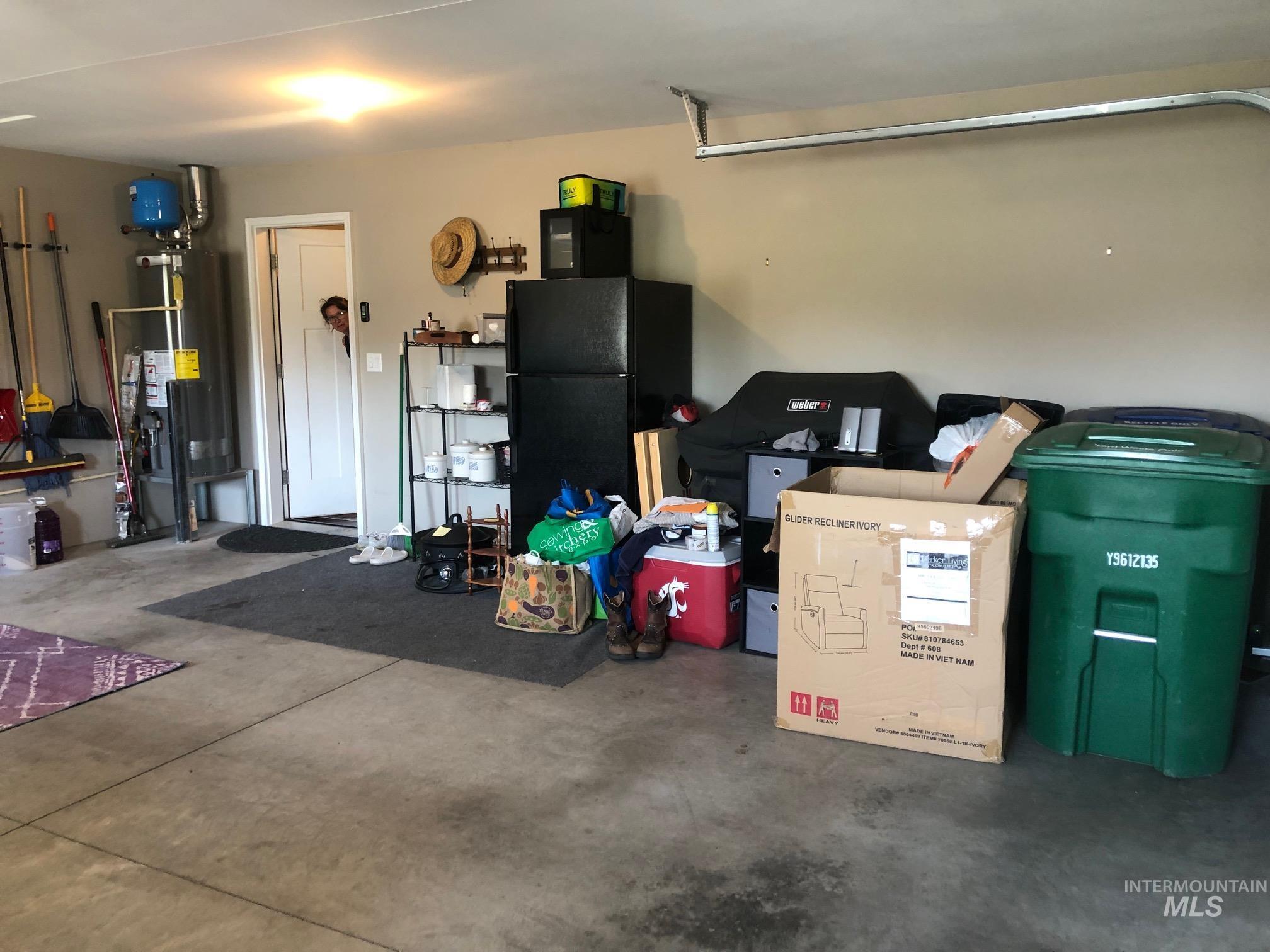 Garage featuring freestanding refrigerator and gas water heater