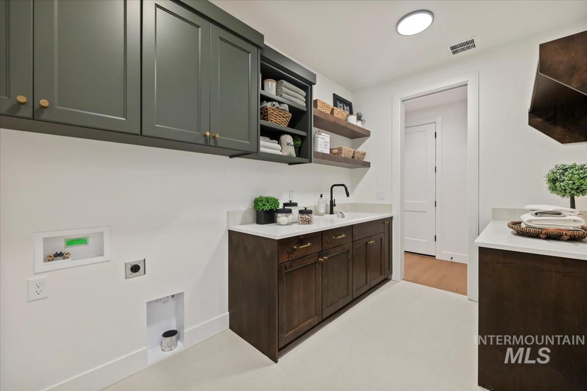 Washroom with hookup for an electric dryer, cabinet space, and washer hookup