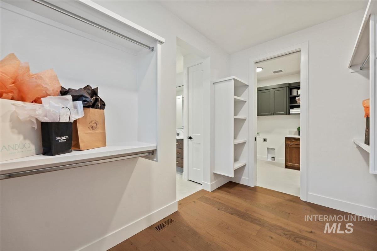 Spacious closet featuring dark wood-style flooring