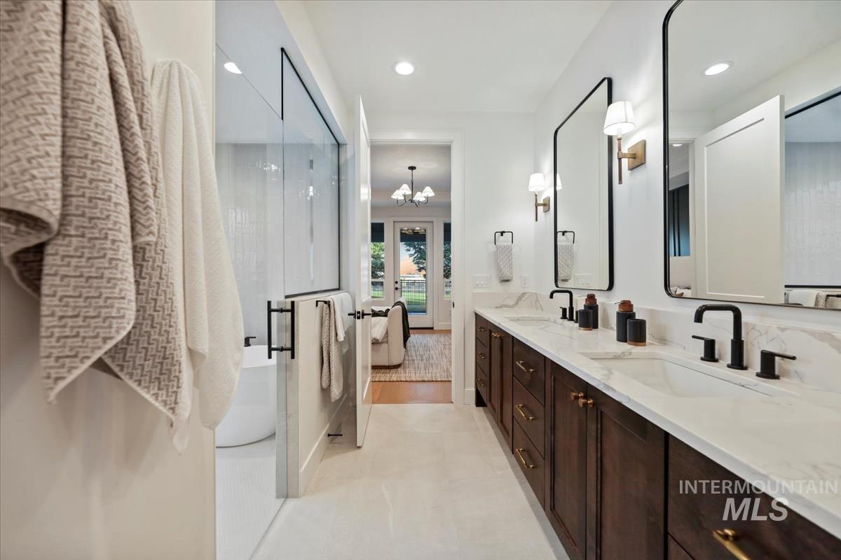 Full bath with ensuite bath, double vanity, a shower stall, recessed lighting, and a chandelier
