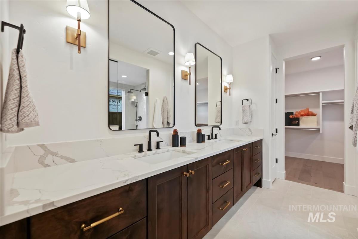Bathroom with double vanity, a stall shower, a spacious closet, and recessed lighting